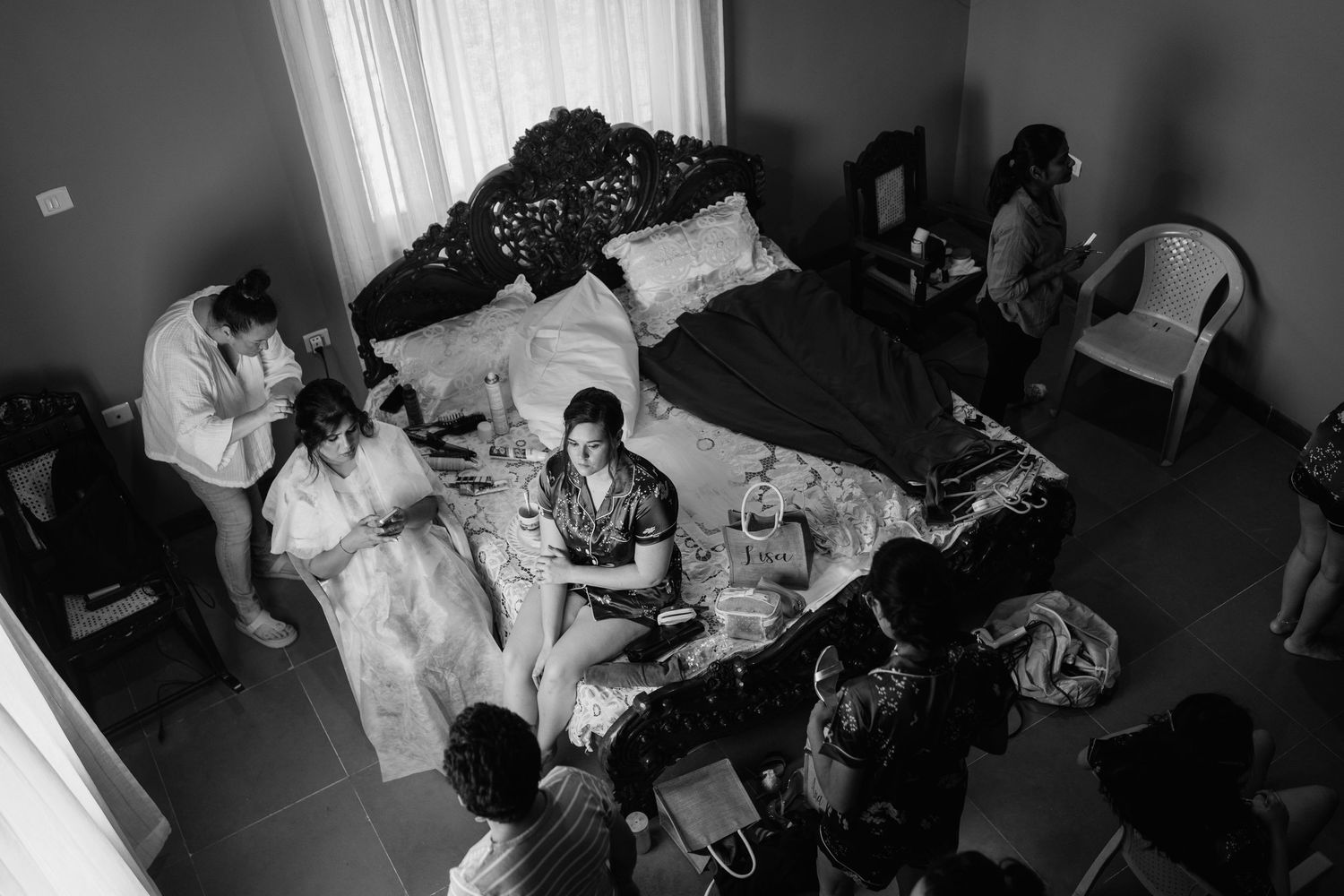 A candid black and white photo showing wedding preparations in a hotel room.