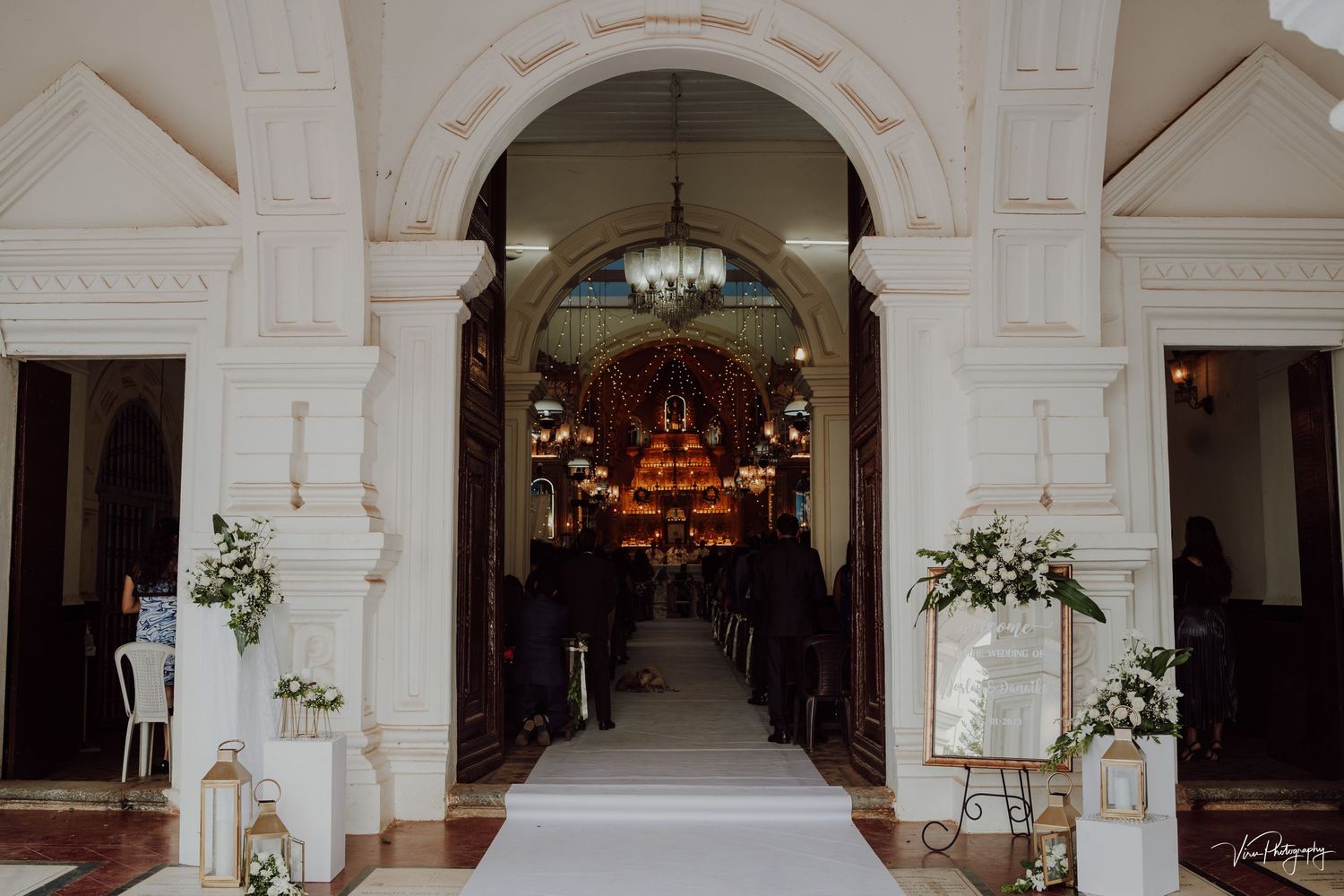 White archway entrance to a church sanctuary decorated with floral arrangements and candles for a wedding ceremony.