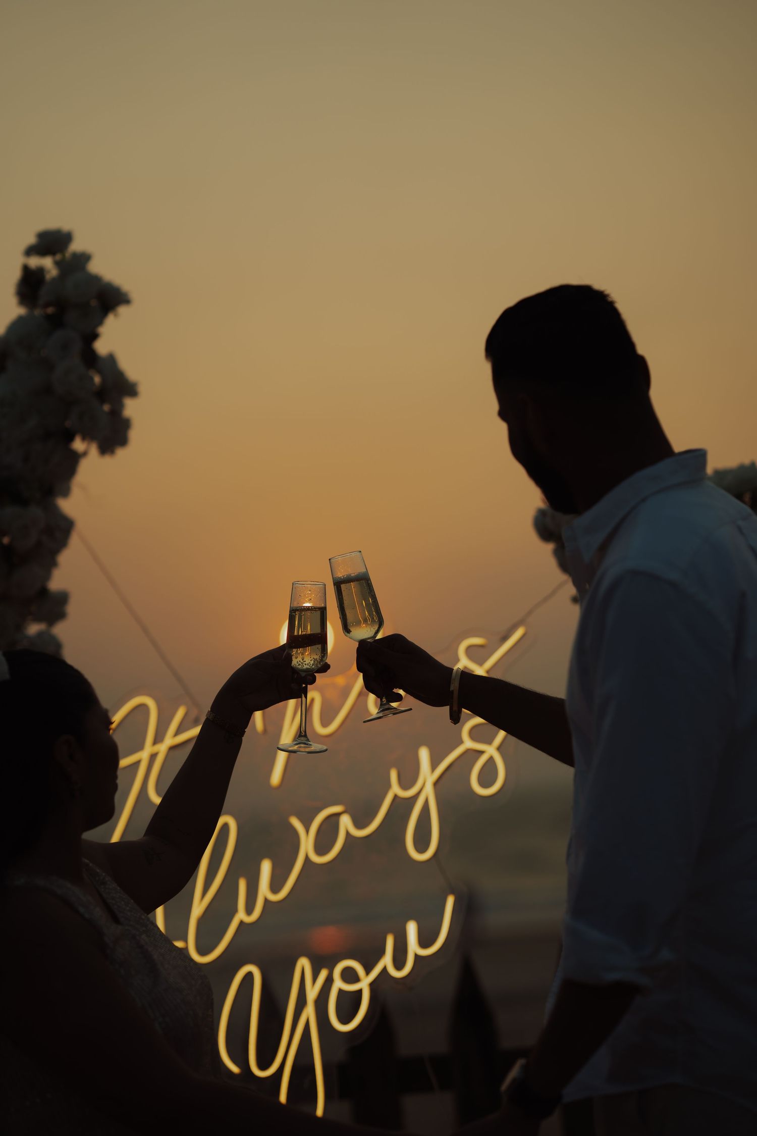 Silhouetted couple toasting champagne at sunset with glowing 