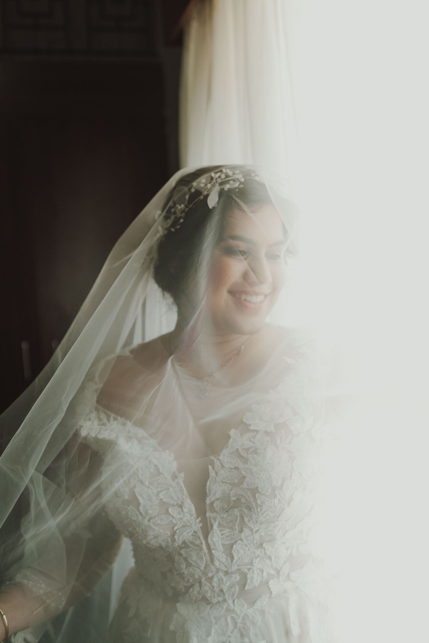 An intimate bridal portrait capturing soft window light through a delicate lace veil.