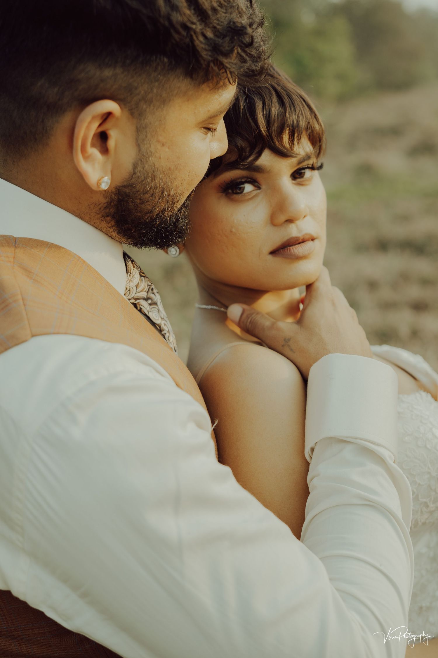 Tender moment between couple during golden hour photoshoot with soft lighting and dreamy atmosphere.