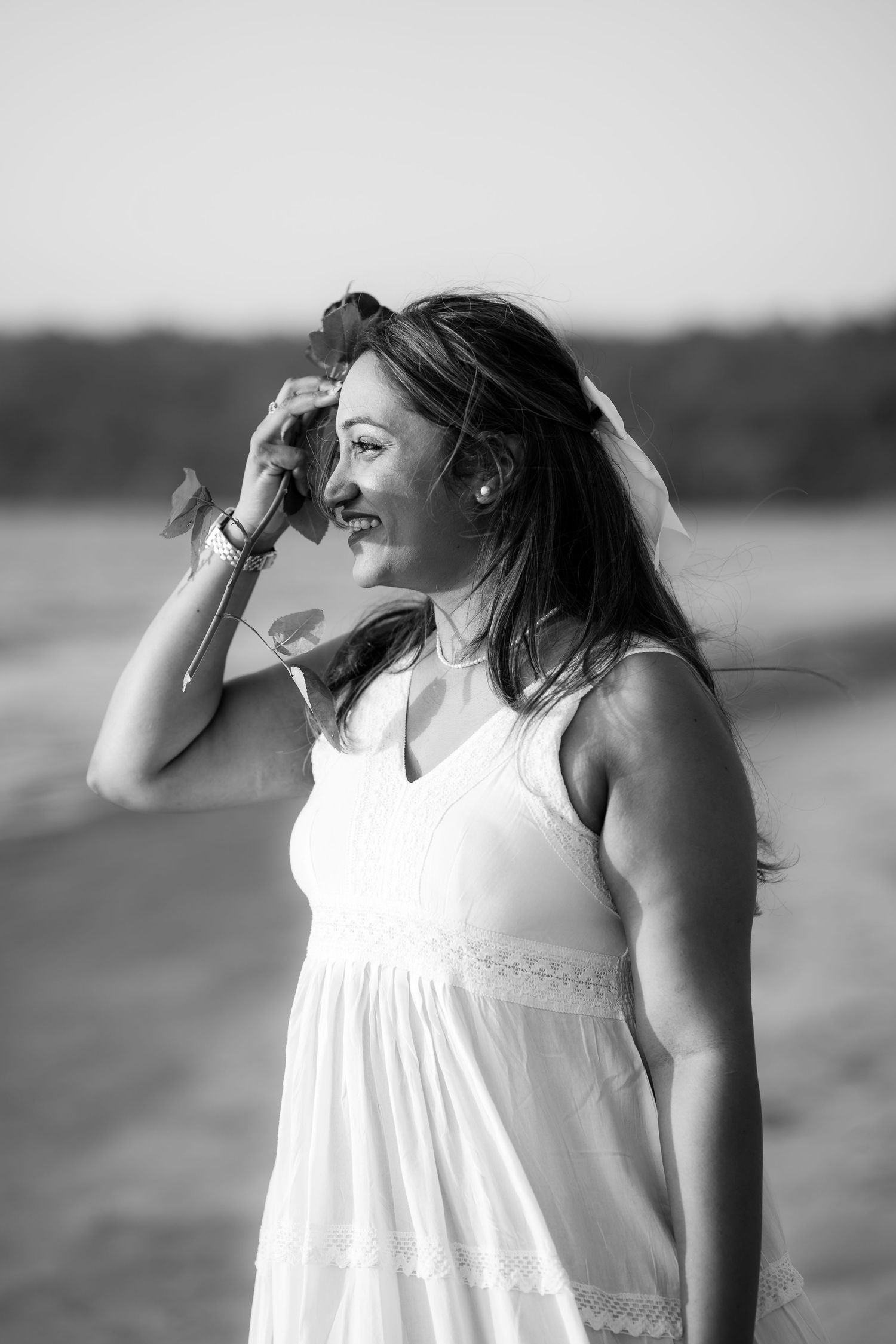 Black and white photo sequence showing a woman in a white dress looking up at the sky by the water.