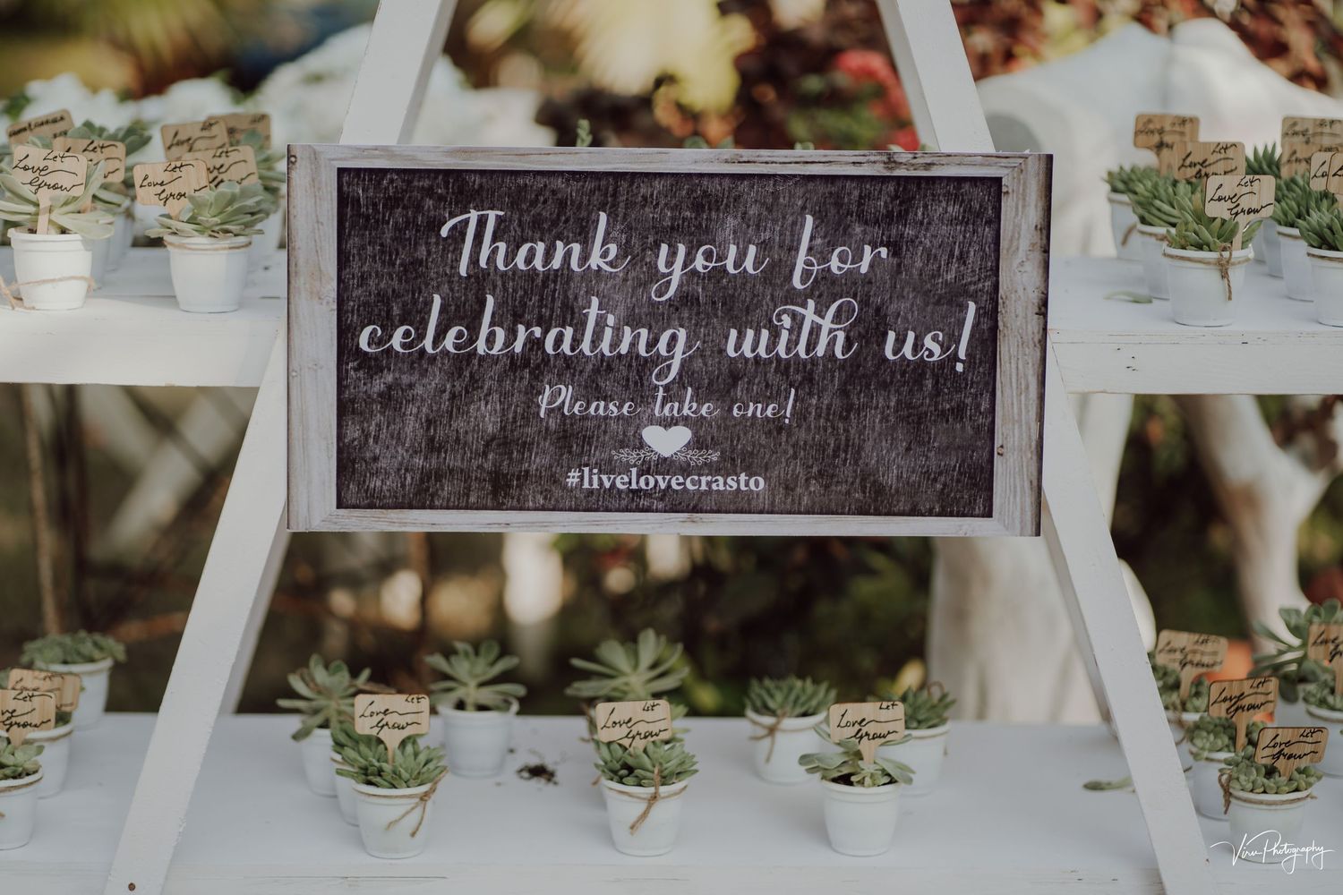 A wedding reception sign reading 'Thank you for celebrating with us' displayed on a table with glass candle holders.