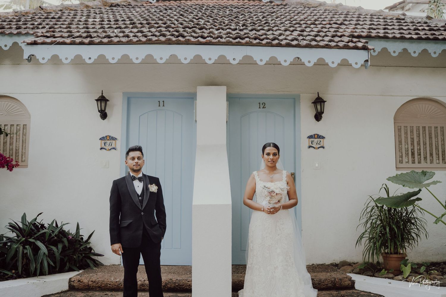 Wedding couple poses separately on either side of a white pillar at a charming Spanish-style home entrance.