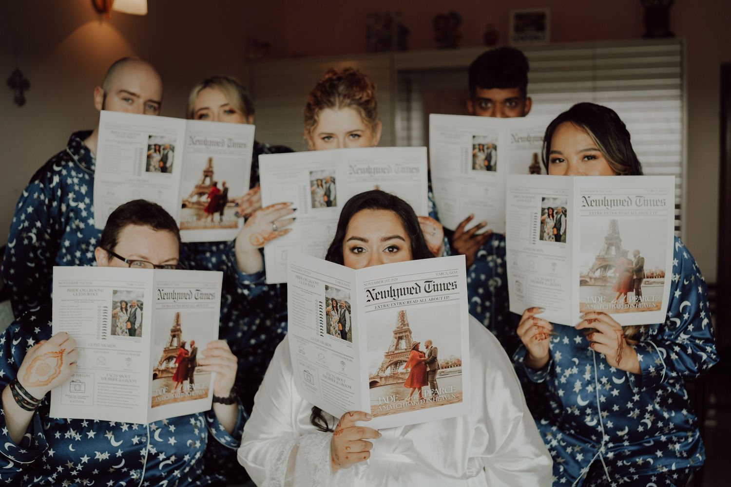 A group holding up newspapers in matching blue robes during a wedding preparation.