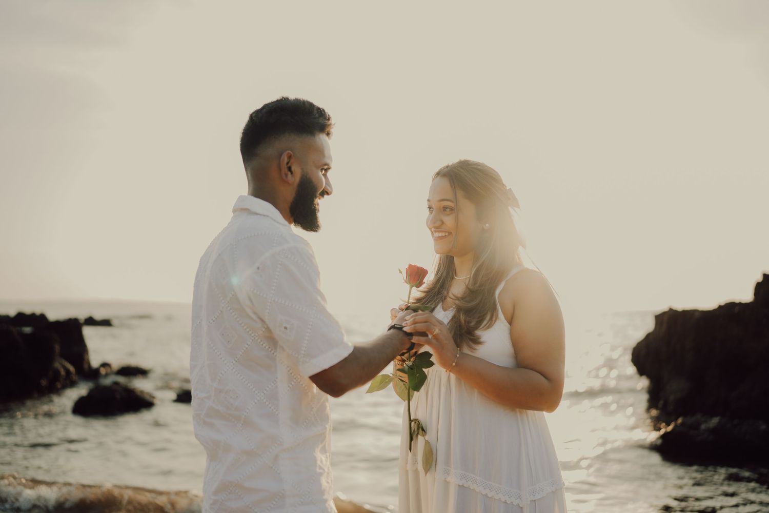 Romantic beach ceremony scene with couple exchanging vows against dramatic coastal backdrop.