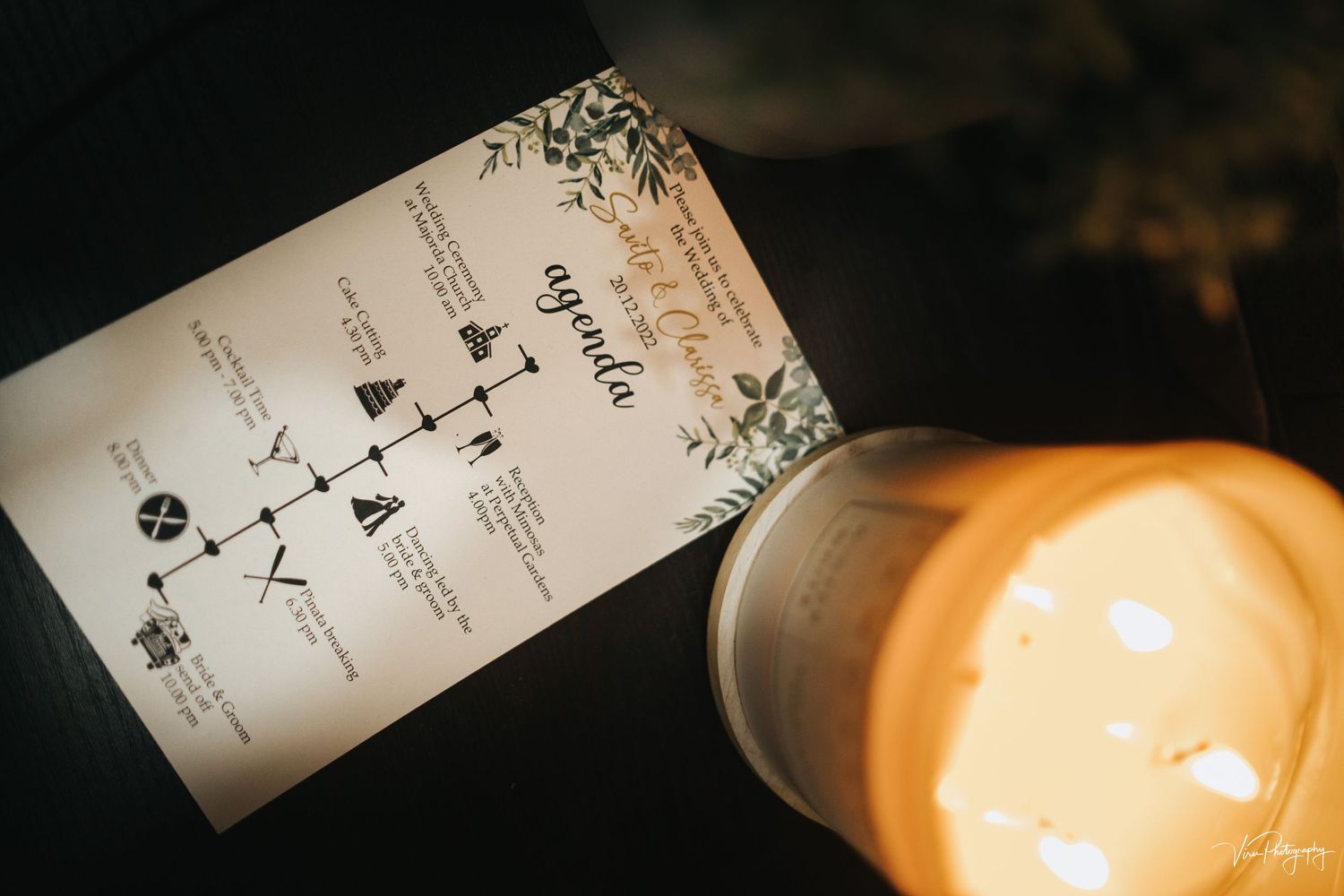 Wedding invitation with a decorative map design lies next to a glowing candle creating a warm atmosphere.