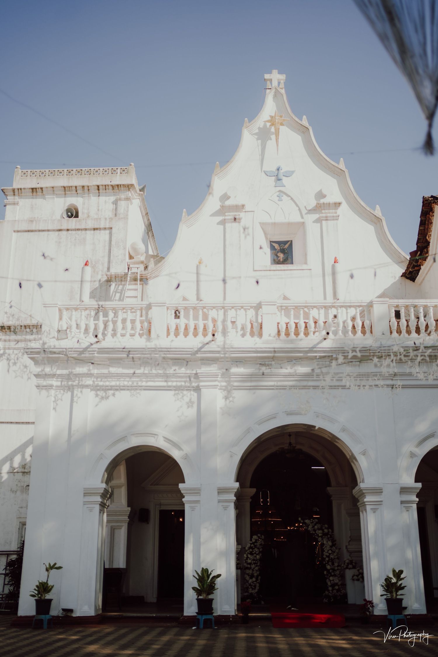 White colonial church facade with arched entrances and ornate architectural details in Portuguese style.