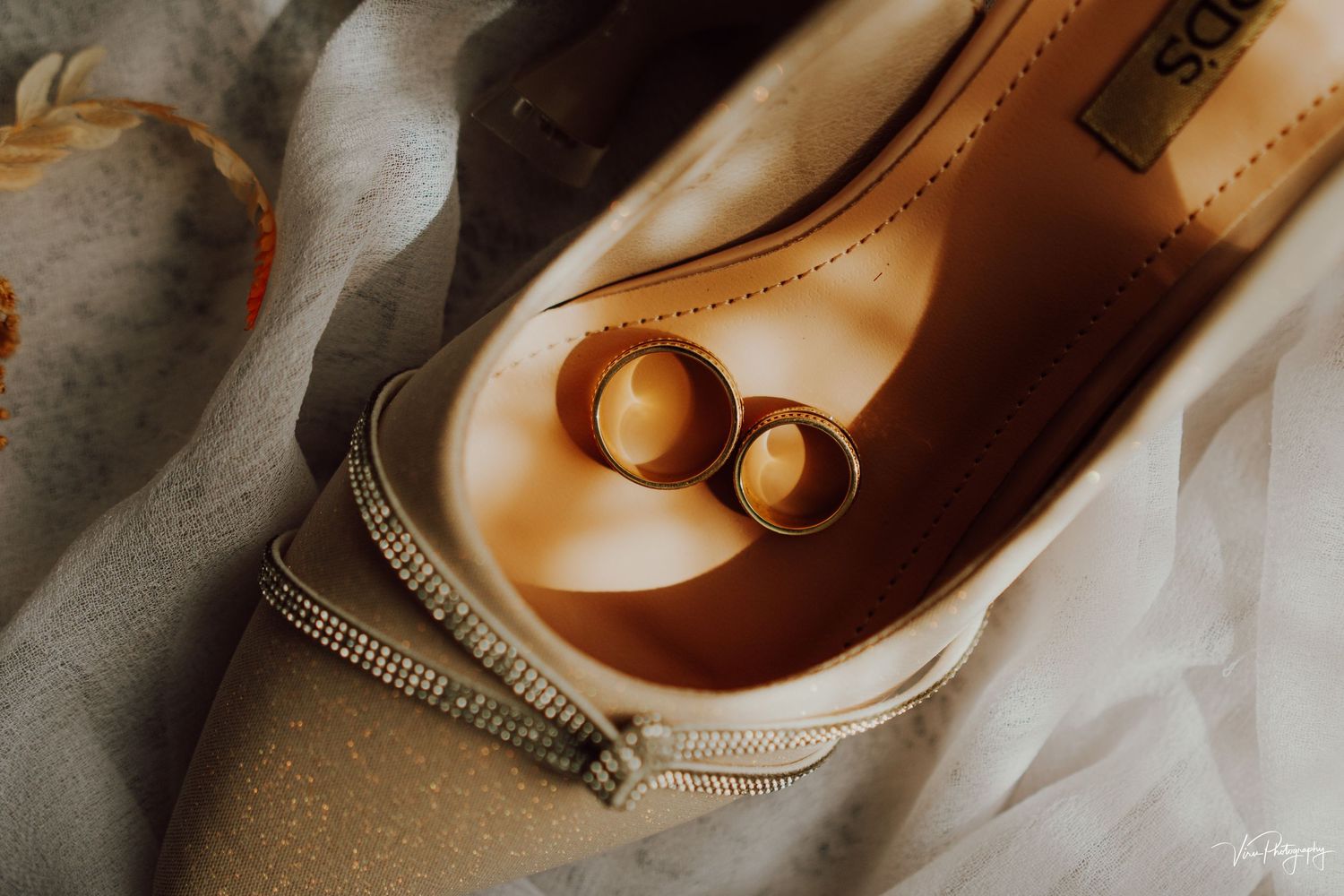 Vintage gold button earrings rest inside a beige leather ballet flat shoe on soft fabric.
