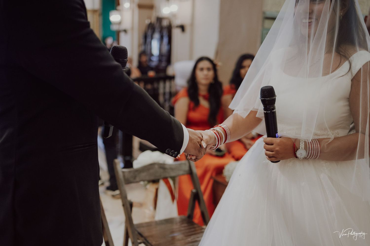 Bride and groom holding hands during wedding ceremony in a church interior.