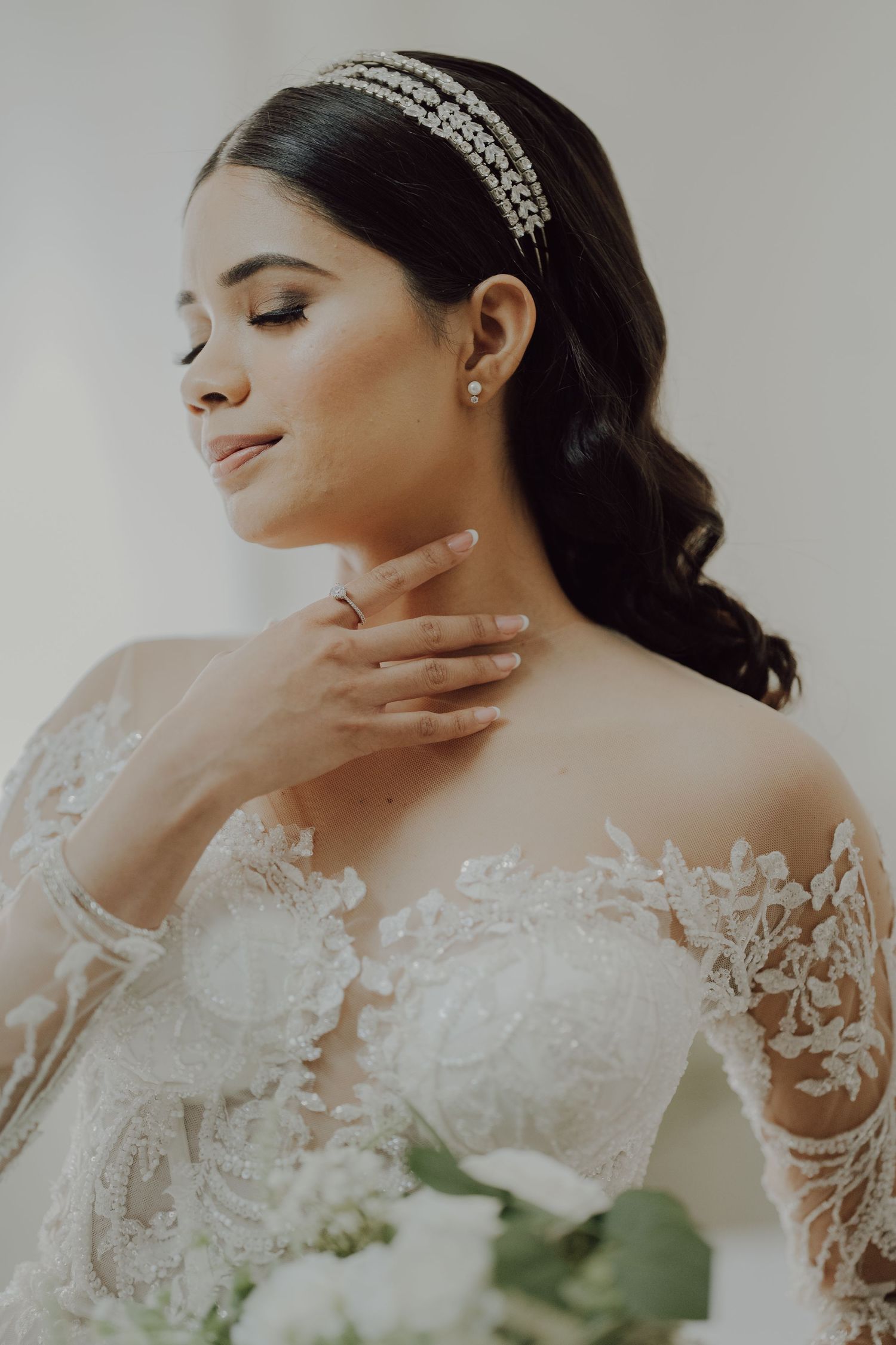 A bridal portrait showcasing elegant lace details and crystal hair accessories.