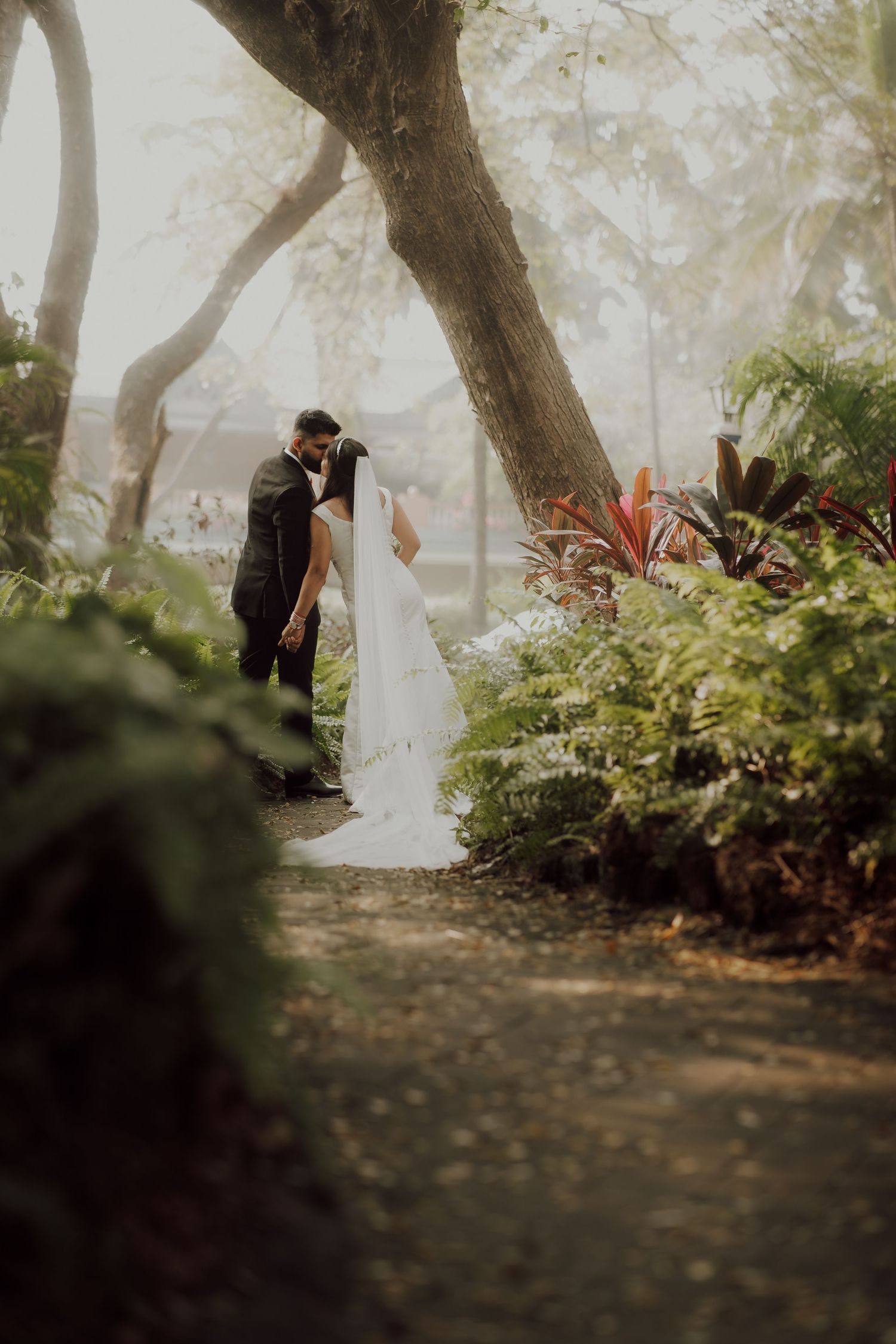 A dreamy wedding photo in a misty forest garden pathway.
