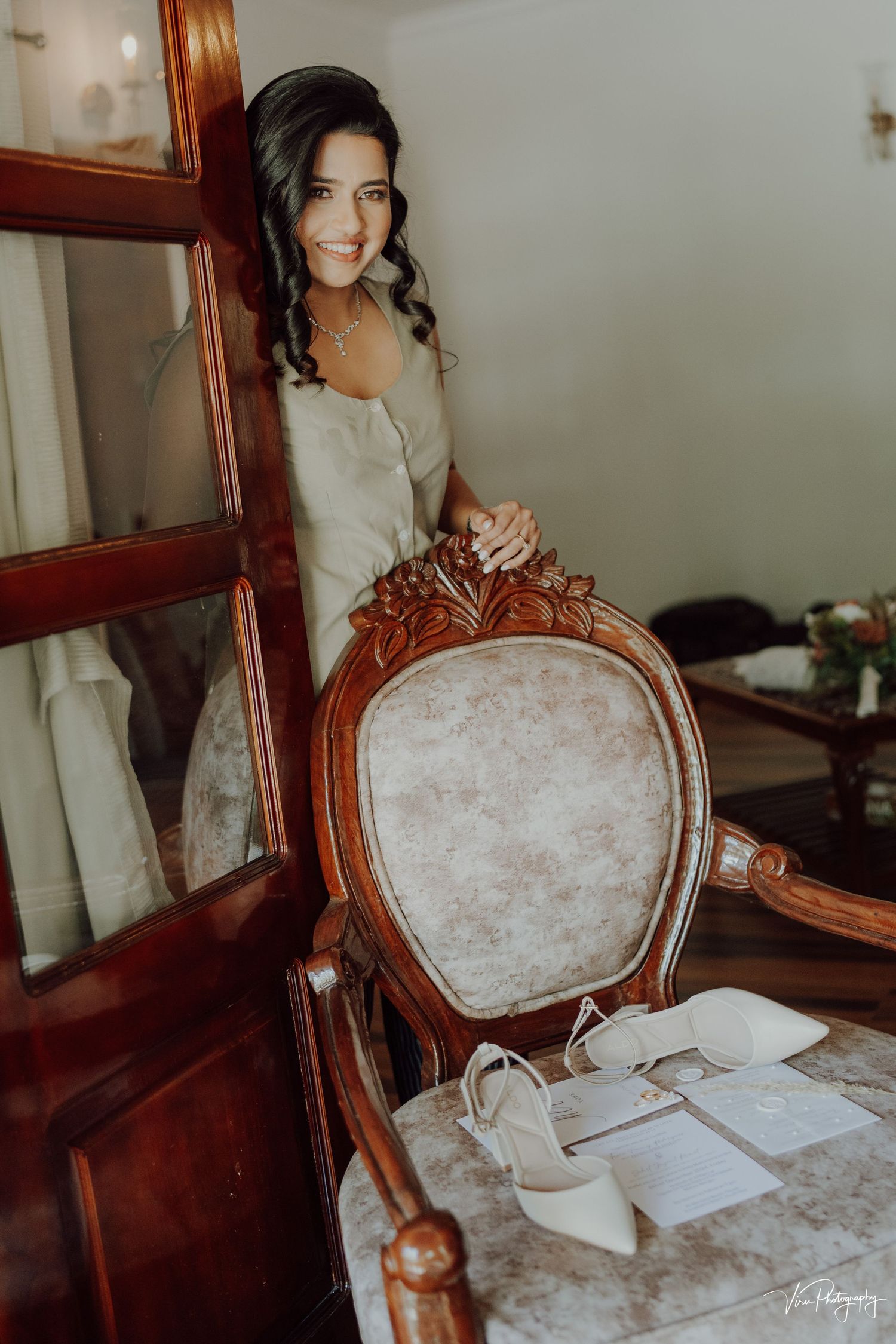 Light floods a vintage room with an ornate wooden chair and someone in an elegant white dress, creating a dreamy atmosphere.