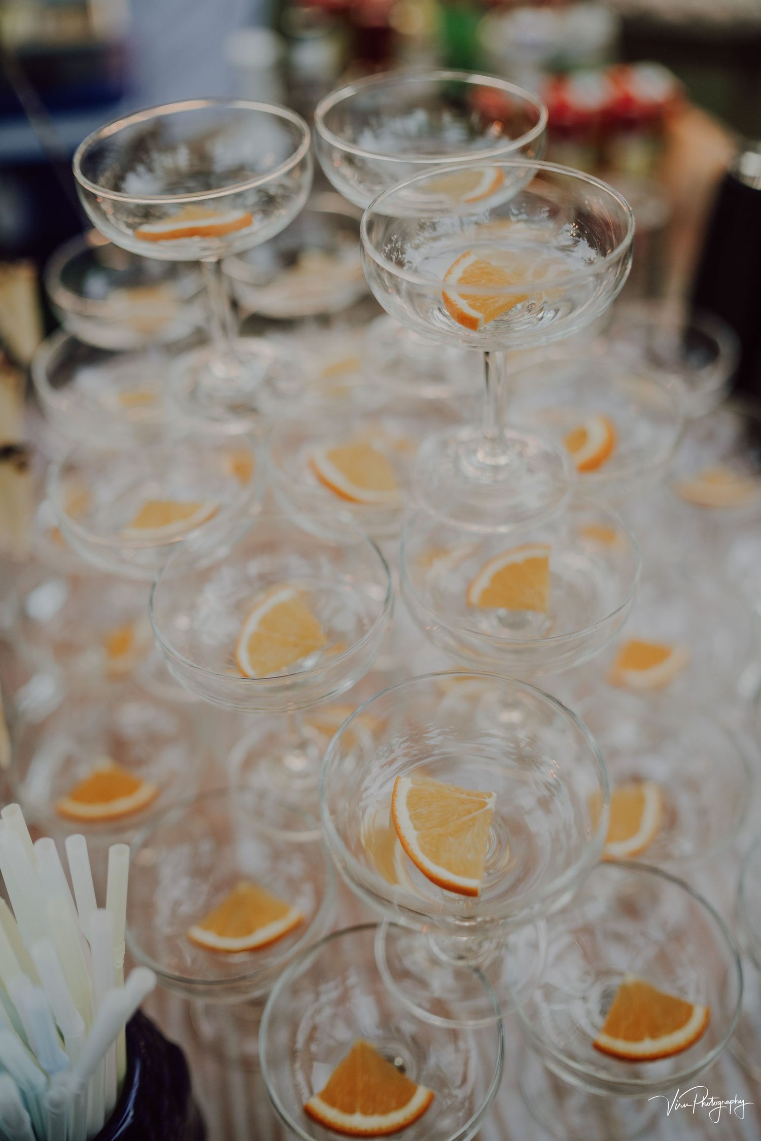 Stacked champagne coupe glasses garnished with orange slices create an elegant cocktail display at a special event.