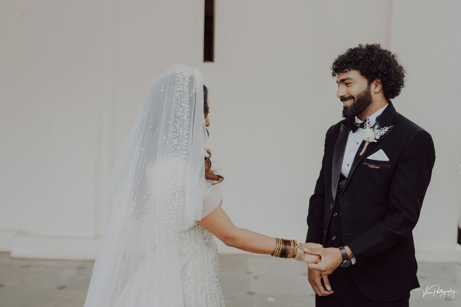 A couple shares a tender moment on their wedding day as they stand together in formal attire with bride in white veil.