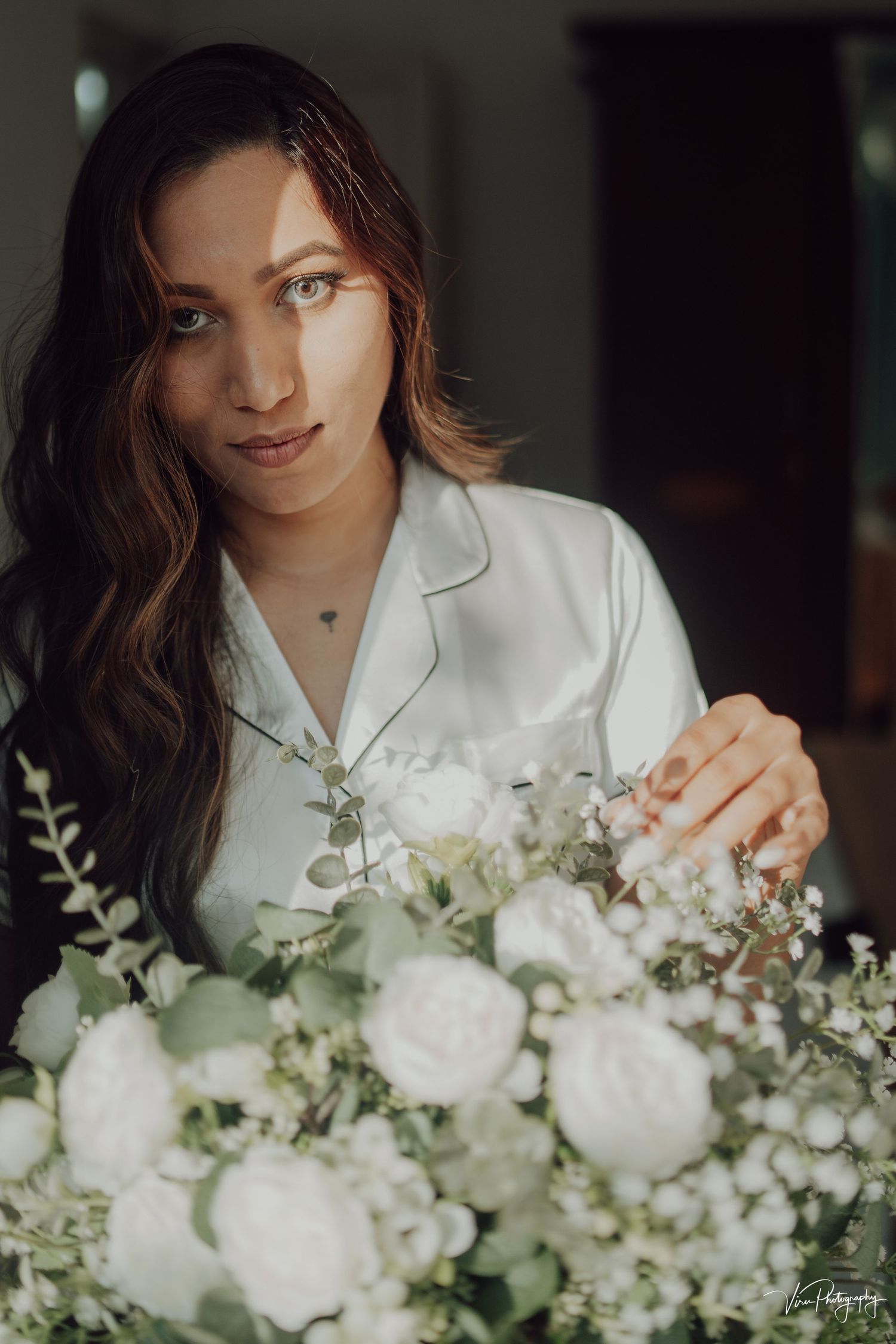Elegant portrait with delicate white floral arrangement featuring soft roses and baby's breath against moody lighting.