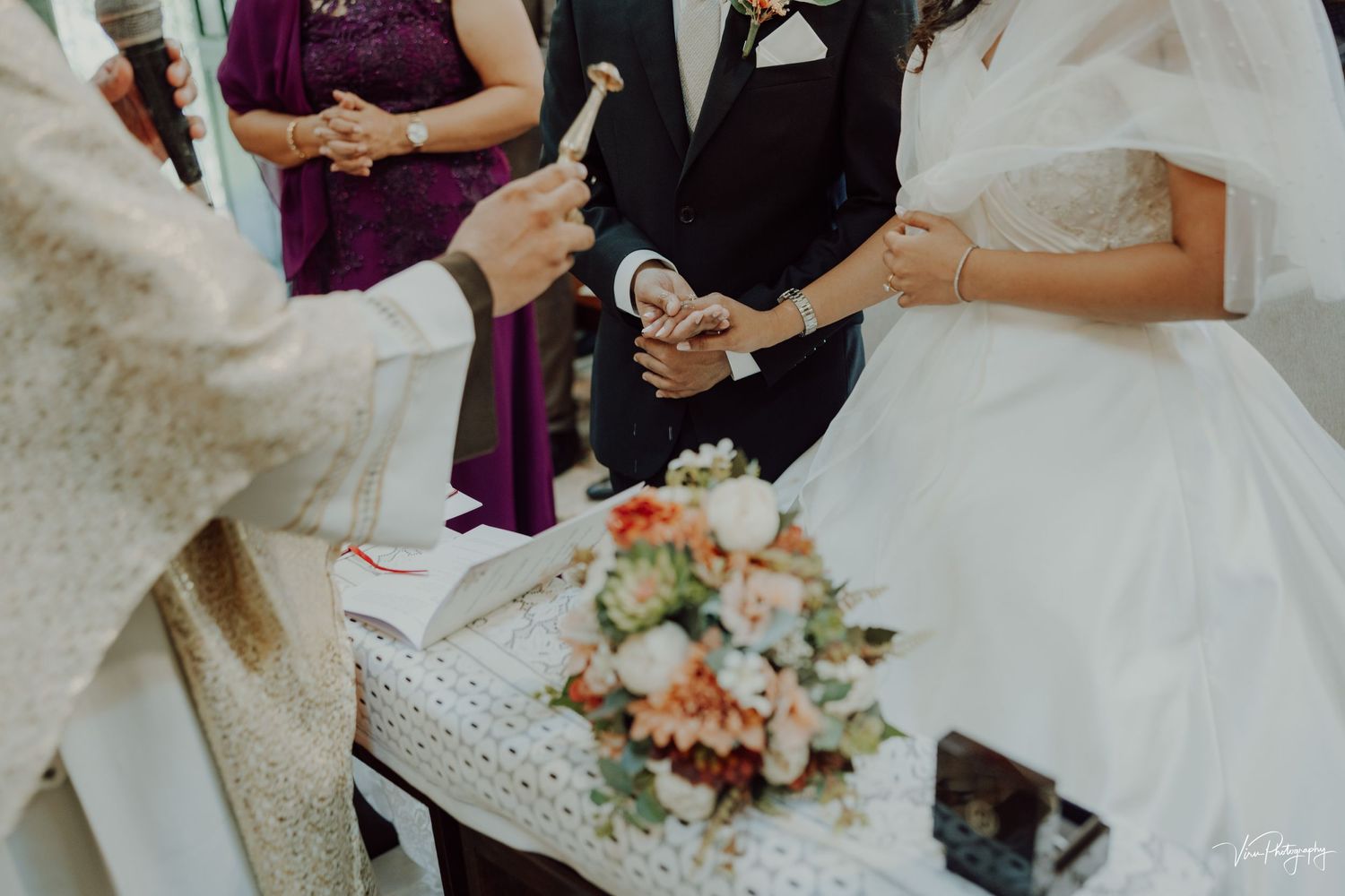 A close-up view of a traditional wedding ceremony with floral bouquet and white gown details during the service.