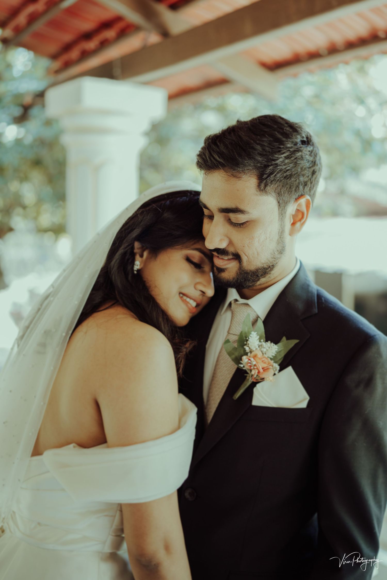 A romantic wedding moment shows a couple in formal attire sharing an intimate embrace under soft lighting.