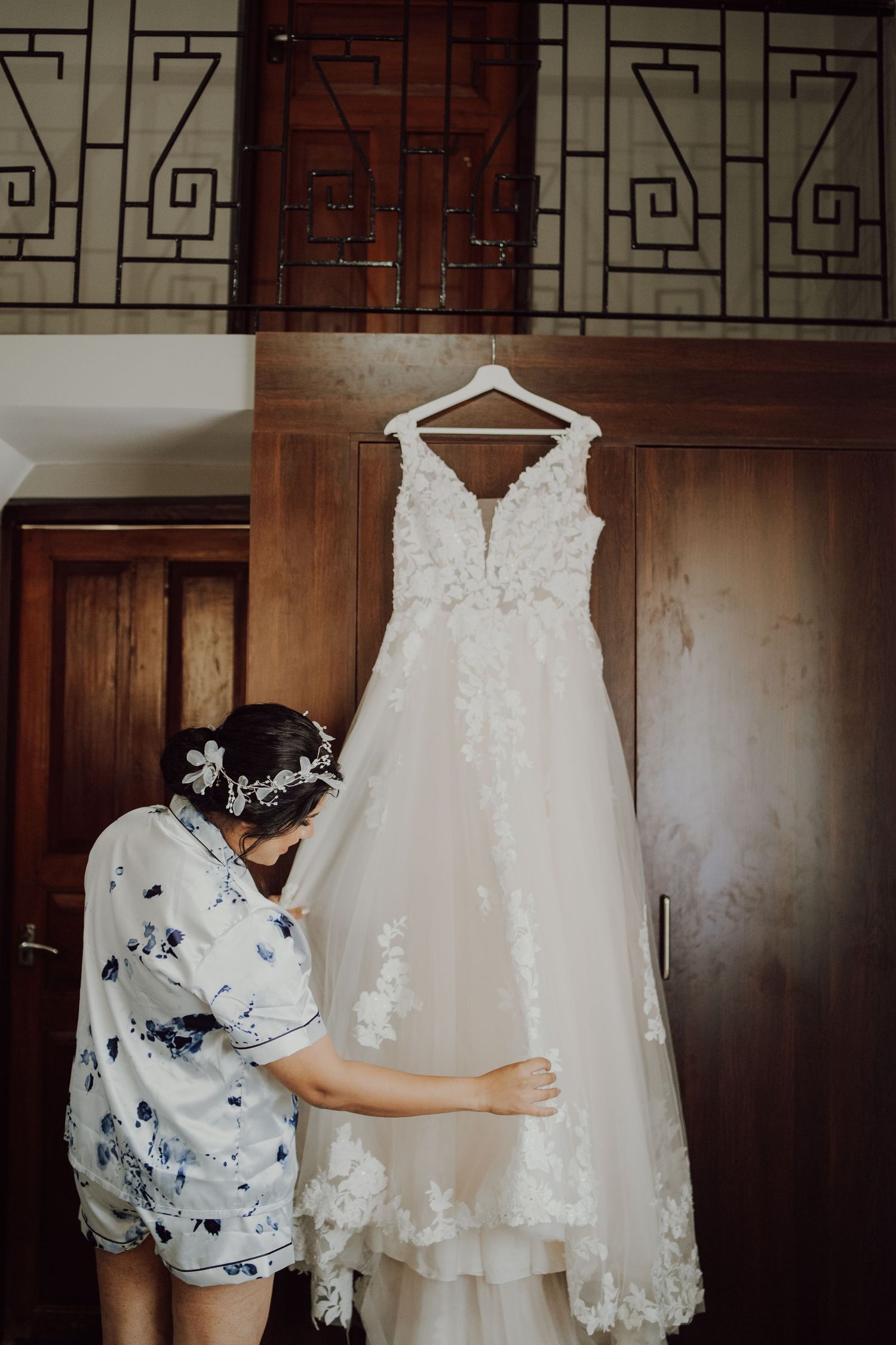 A close-up view of someone admiring an elegant white lace wedding dress hanging on display.