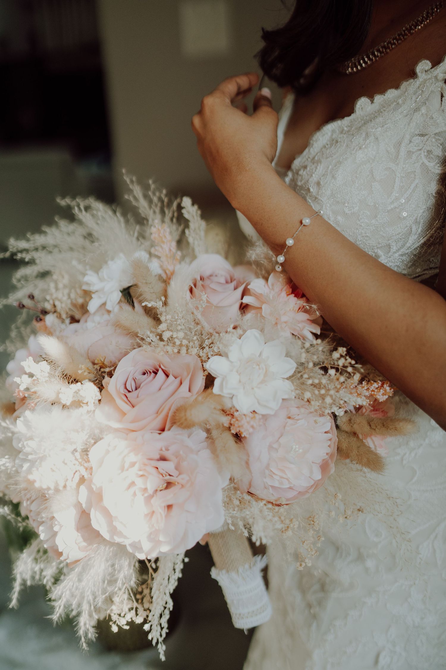 Close-up of blush pink and white wedding bouquet with roses and pampas grass.