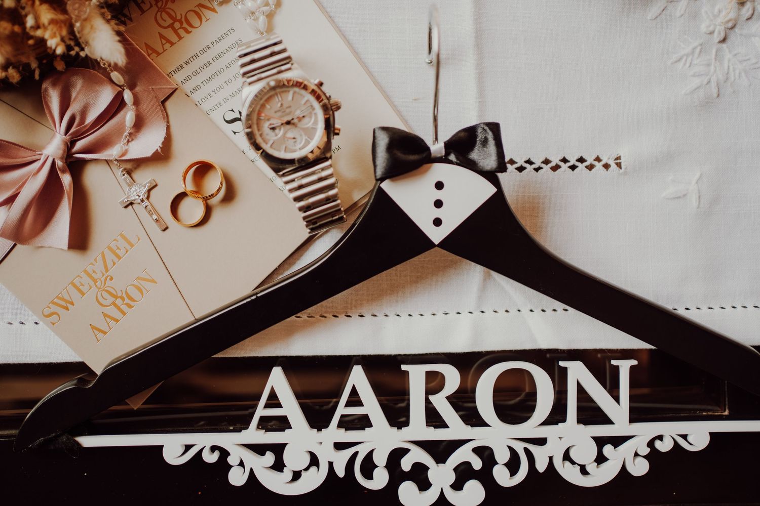 Wooden hanger with 'AARON' text displayed with wedding rings and decorative elements.