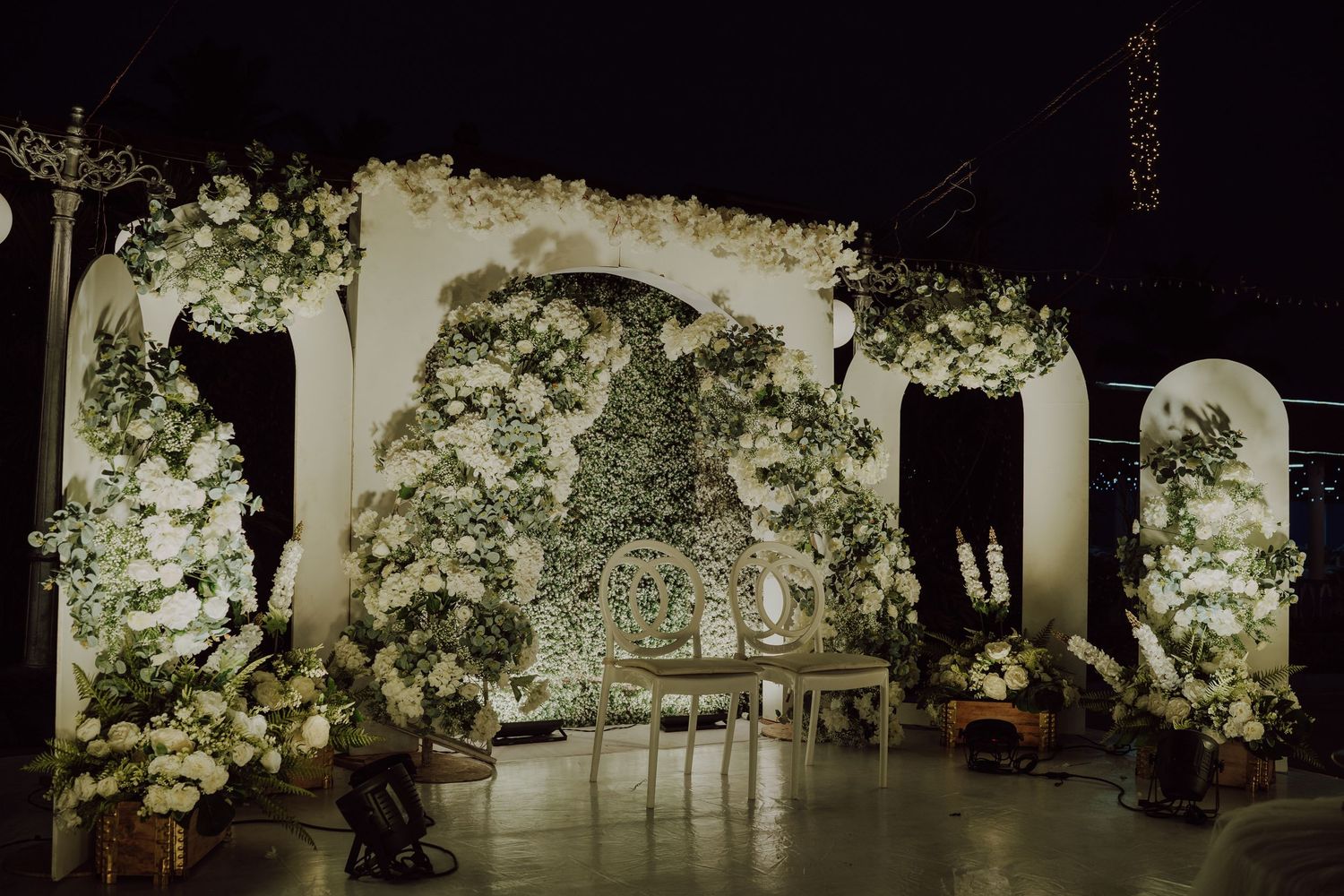 Elegant white floral archways and decor create a romantic wedding ceremony setting.