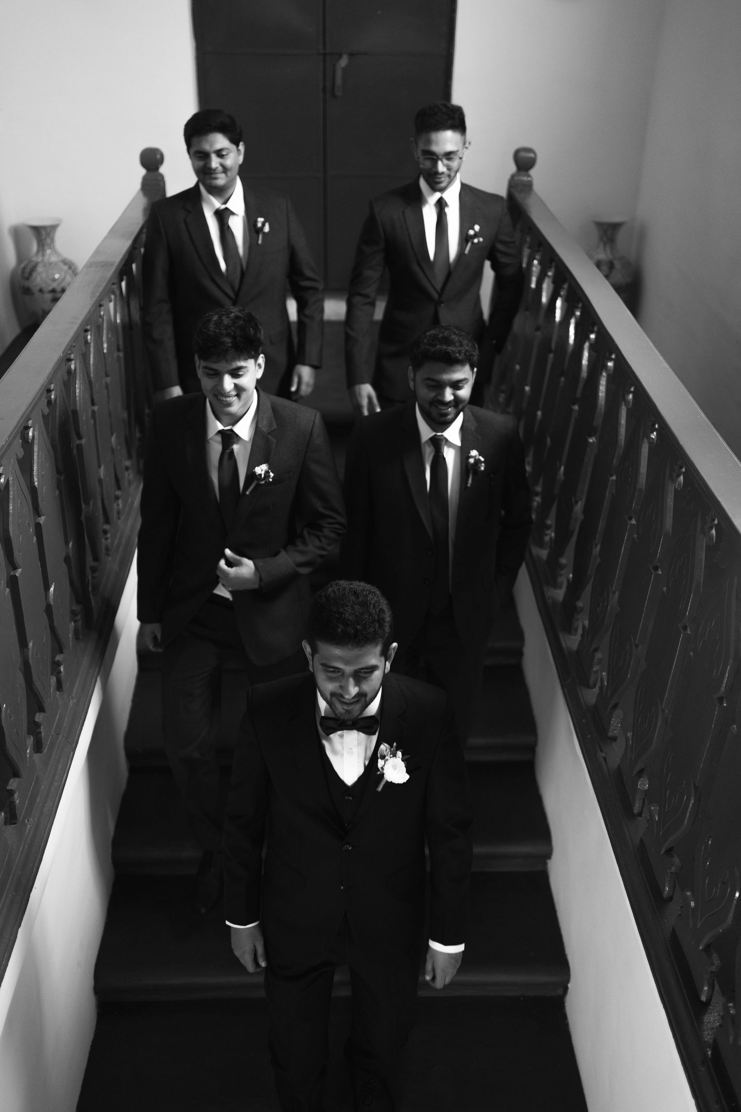 Formal group photo on wooden stairs in black and white.
