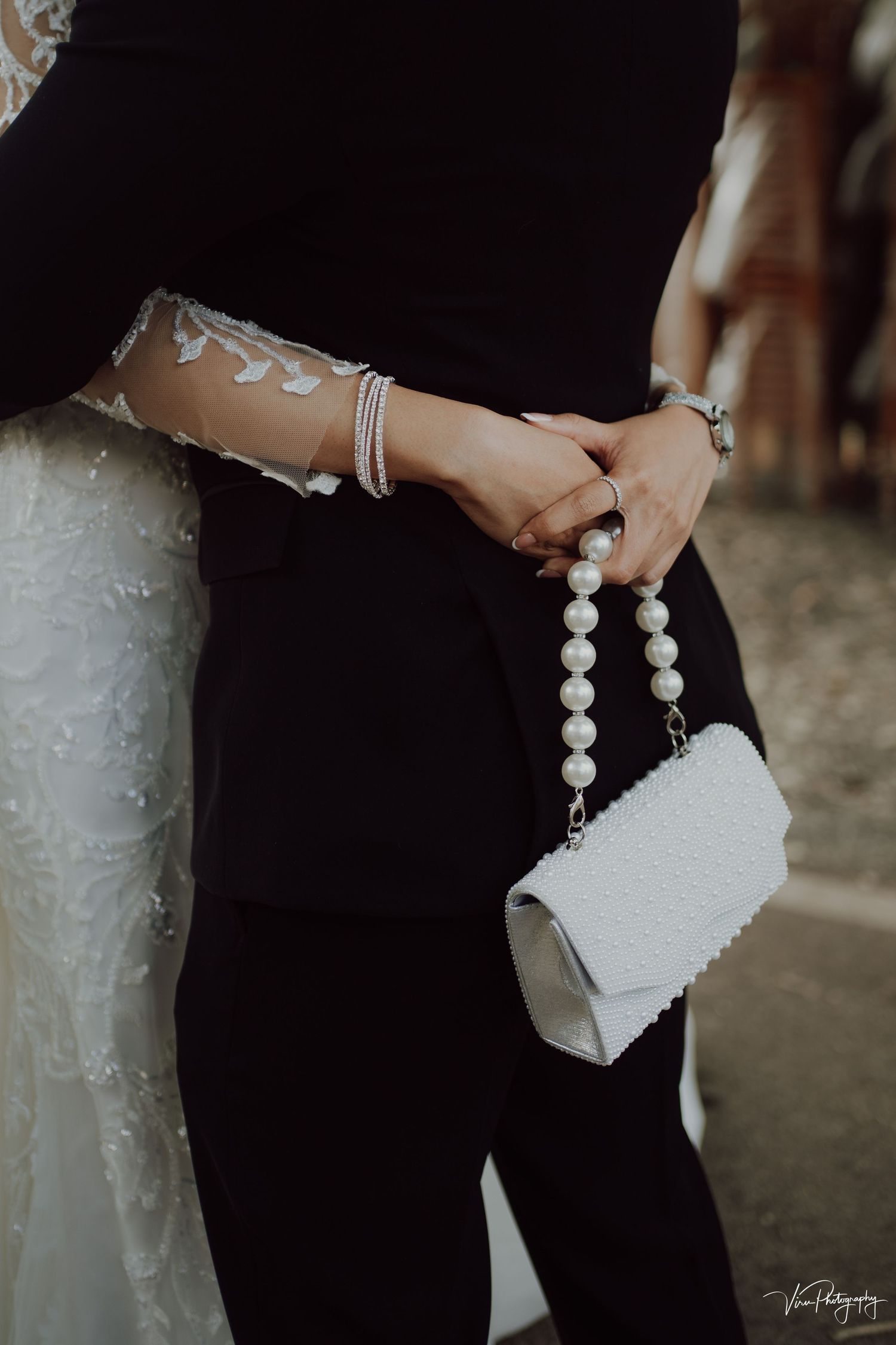 Woman holding elegant white clutch purse with pearl handle detail during formal event.