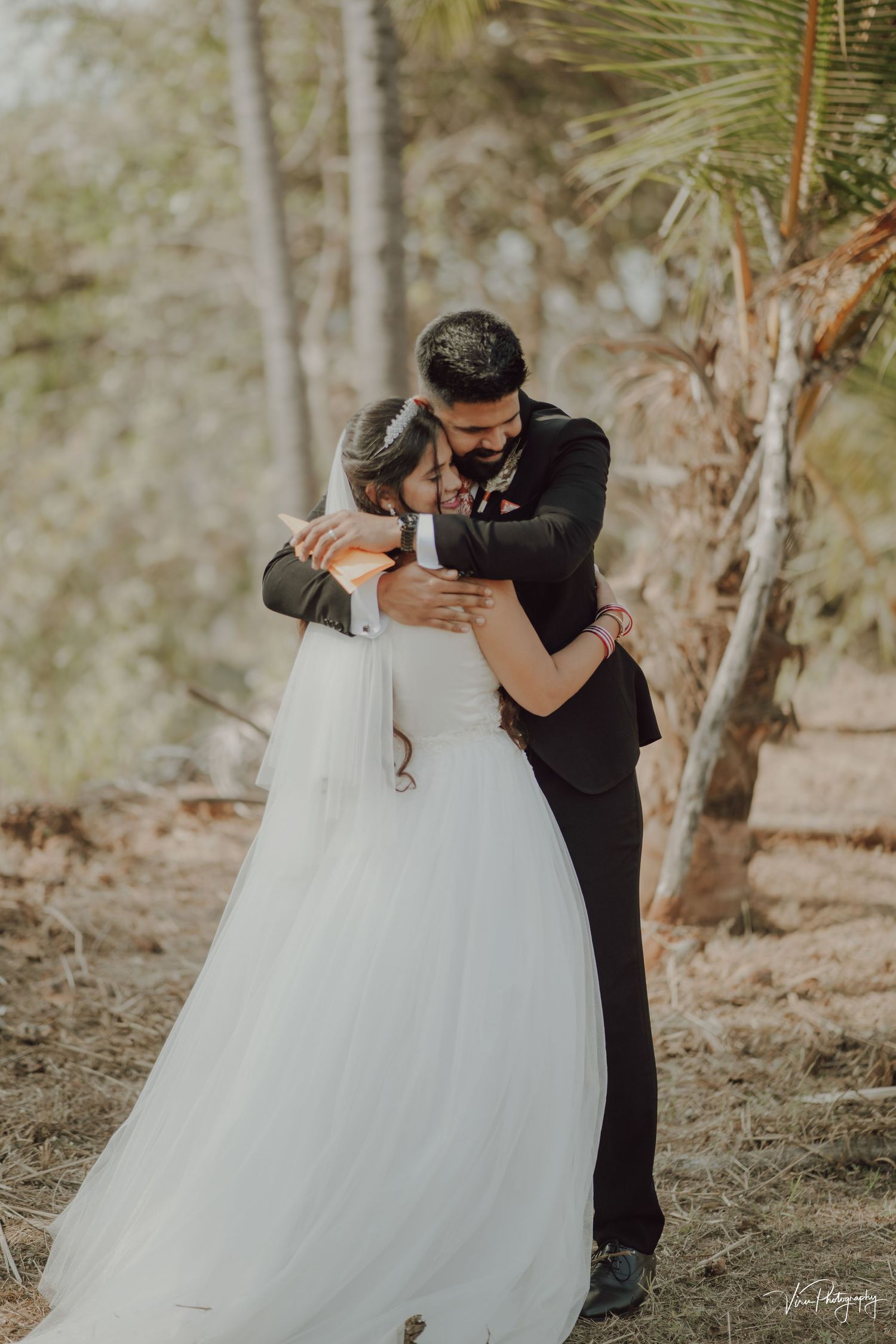 A romantic outdoor wedding scene with a couple embracing among palm trees and natural scenery.