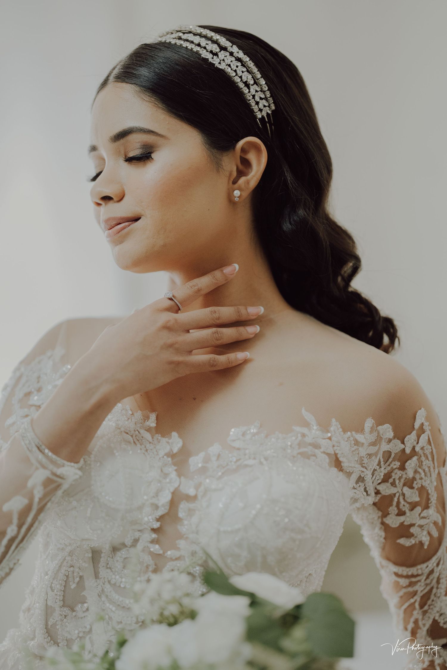 Elegant bridal portrait featuring delicate lace off-shoulder gown and sparkly headpiece against soft natural lighting.