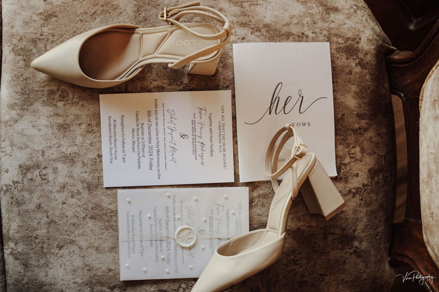 Wedding day details including white heels, gold wedding rings, and elegant invitation cards on a textured surface.