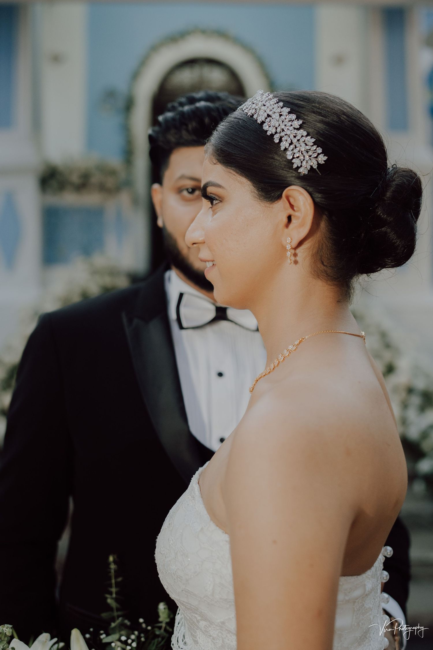 Elegant bride in strapless gown wearing a crystal hair accessory and delicate necklace on her wedding day.