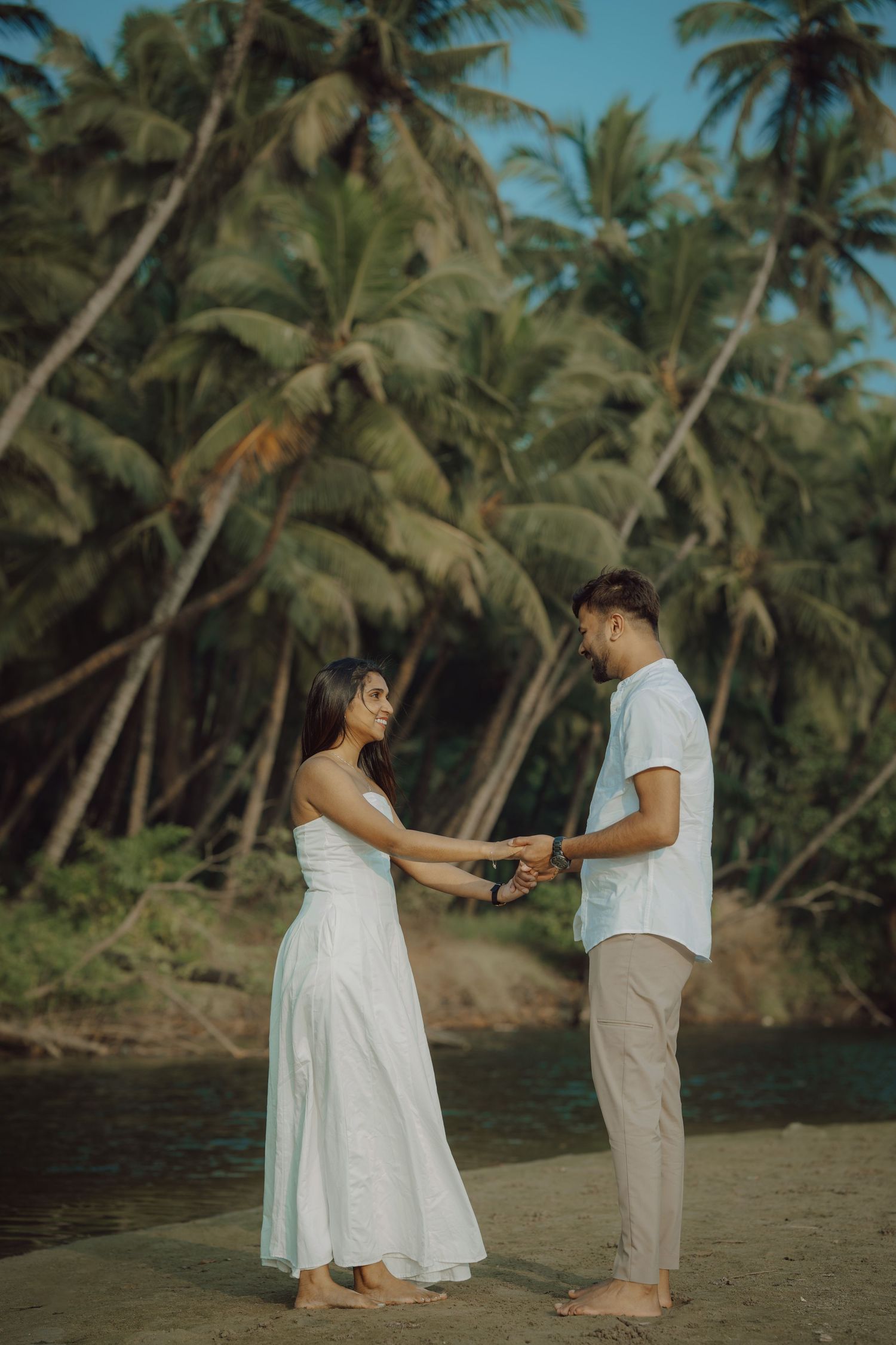 A couple shares a romantic moment on a tropical beach with palm trees swaying in the background.
