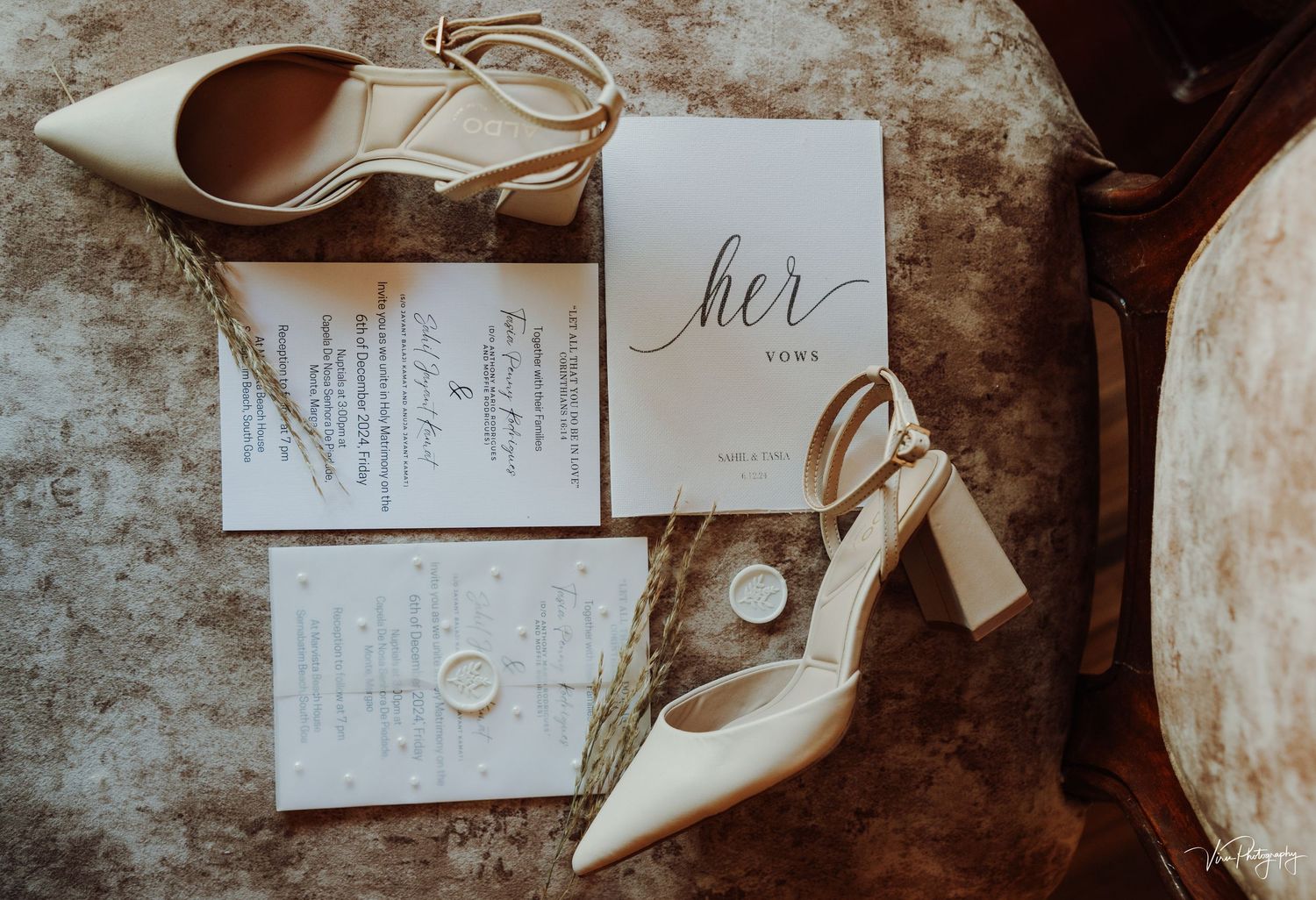Wedding details flatlay with ivory heels, invitation suite and 'her' card on vintage textured surface.