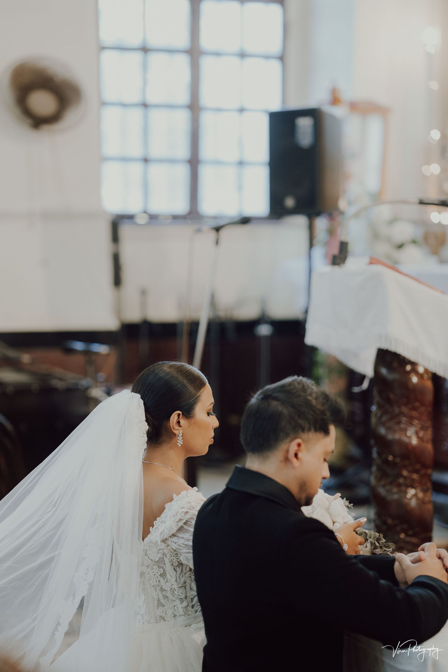 A couple shares an intimate moment at their wedding reception, with the bride wearing a flowing white veil.