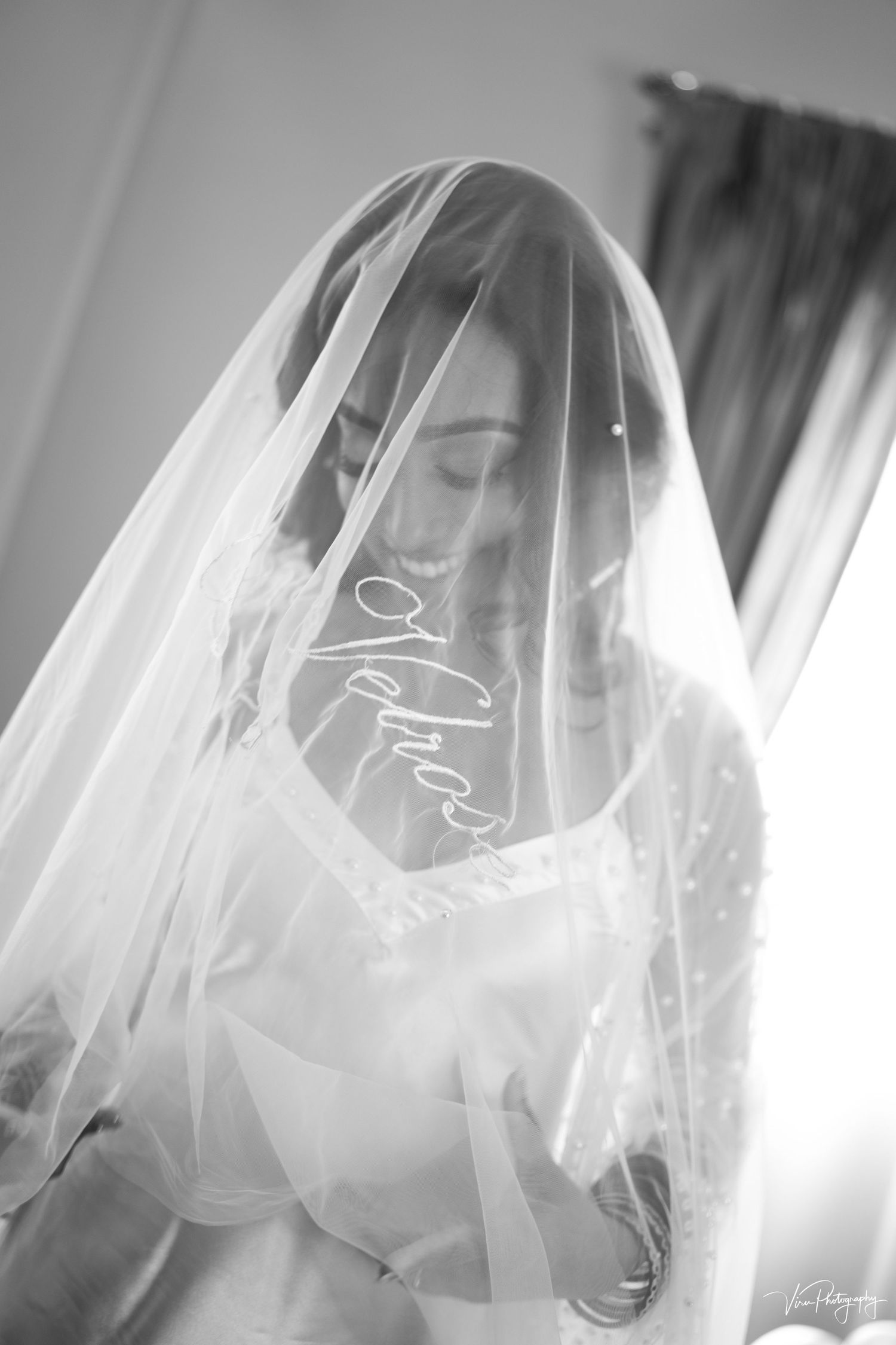 Ethereal black and white bridal portrait with delicate veil creating dreamy, softly lit atmosphere.
