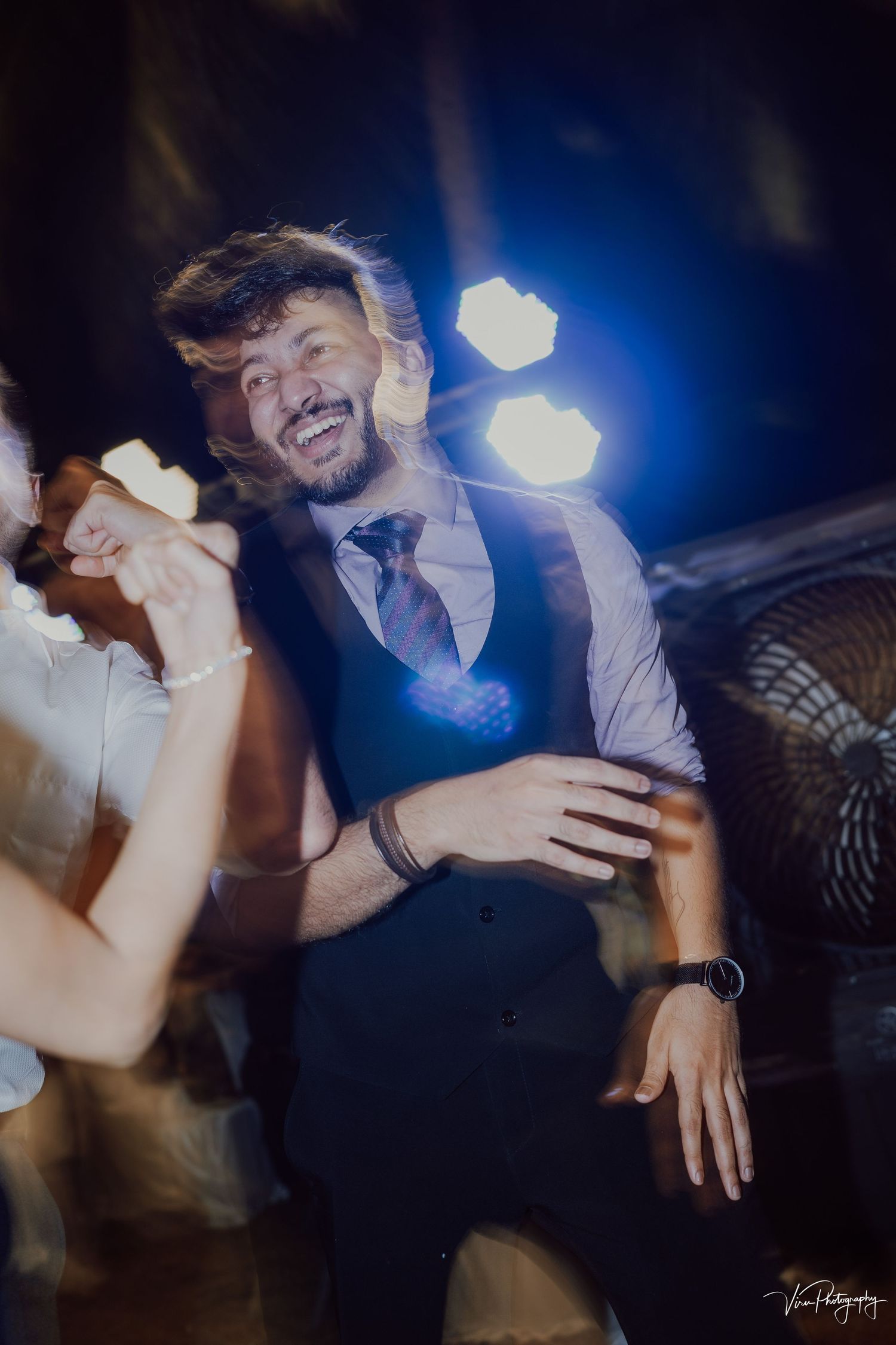 Blurred motion party photo with bokeh lights showing person dancing and laughing at nighttime celebration.