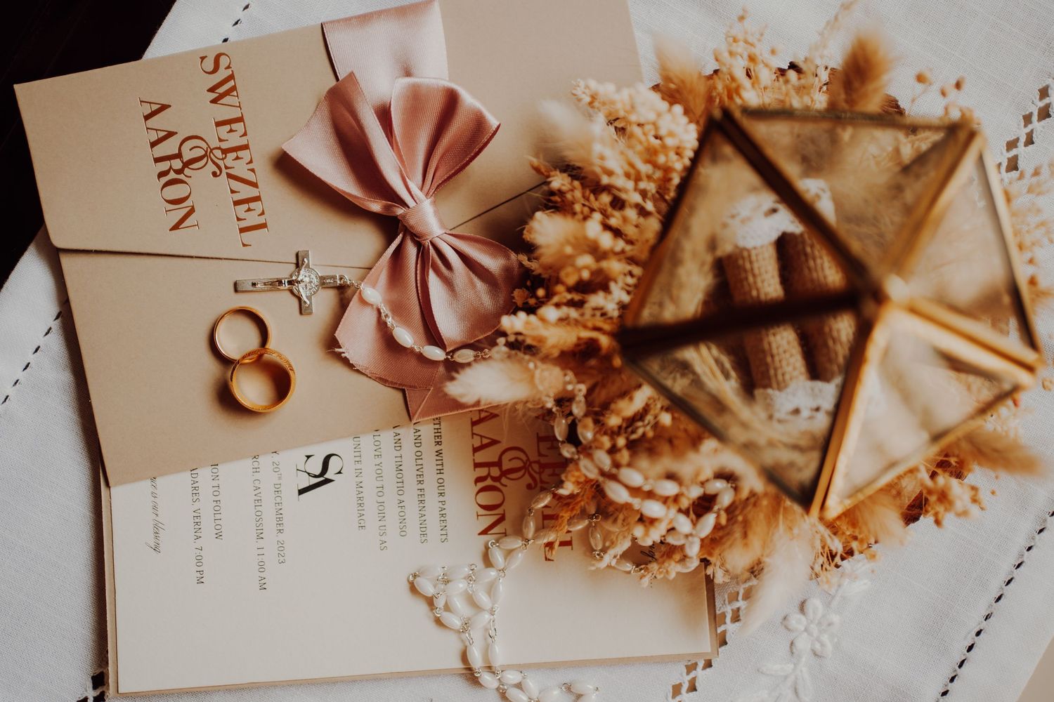 Wedding stationery with pink bow and rings styled with dried floral elements.