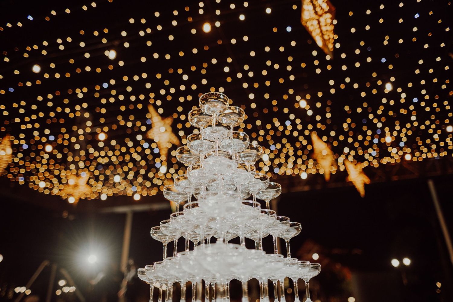 Elegant tiered white wedding cake under sparkling fairy light display.
