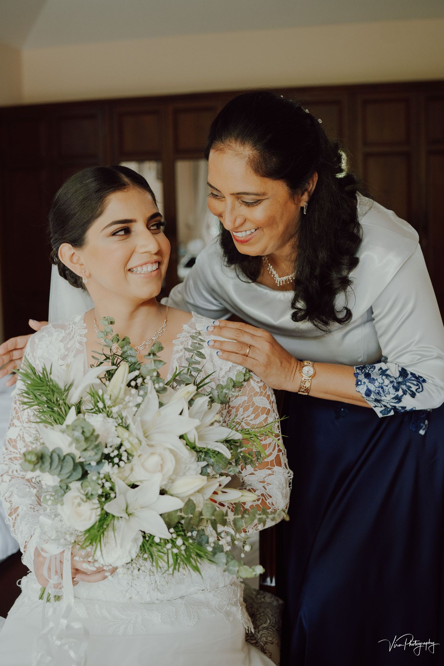A heartwarming moment between two people sharing smiles with a beautiful white and green bridal bouquet.