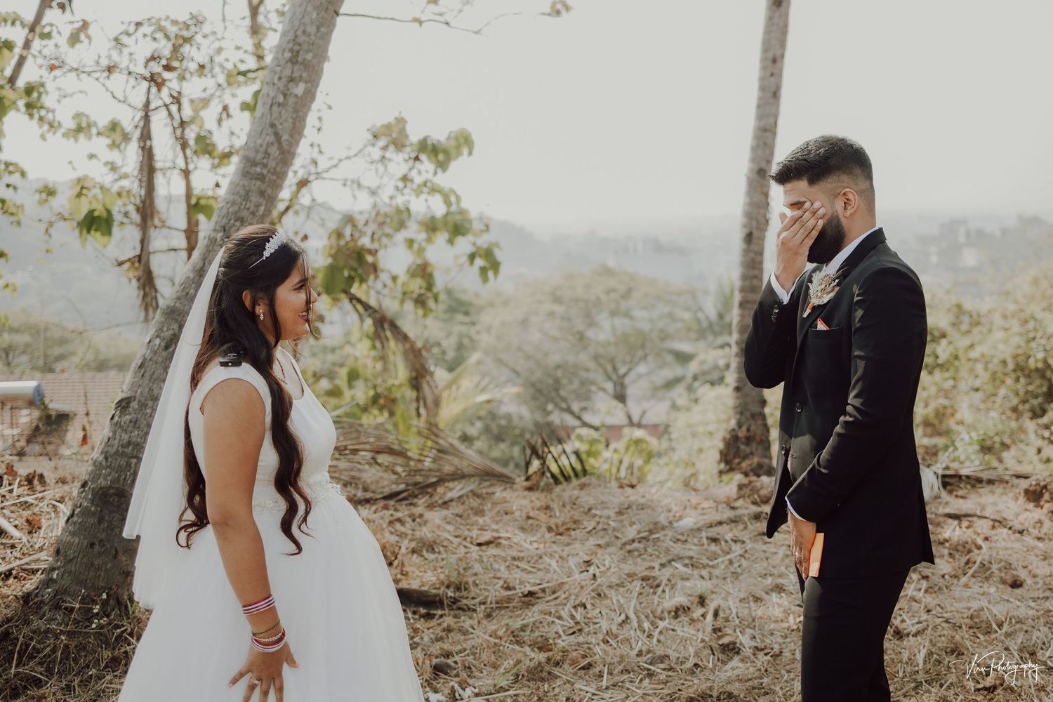 A couple shares their first look moment on a hilltop during their wedding photoshoot.