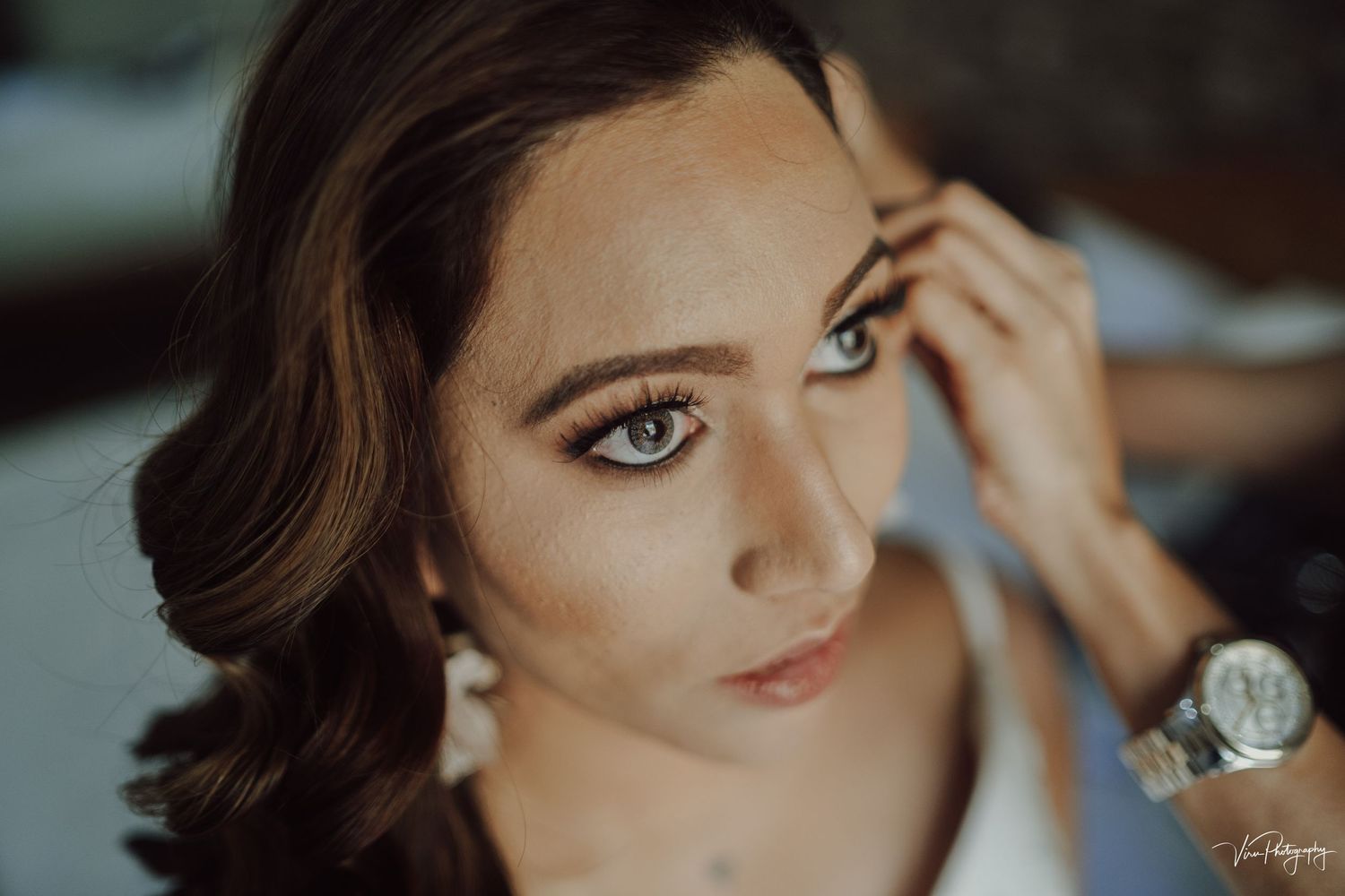 Professional makeup artist applies finishing touches during a dramatic beauty photography session indoors.