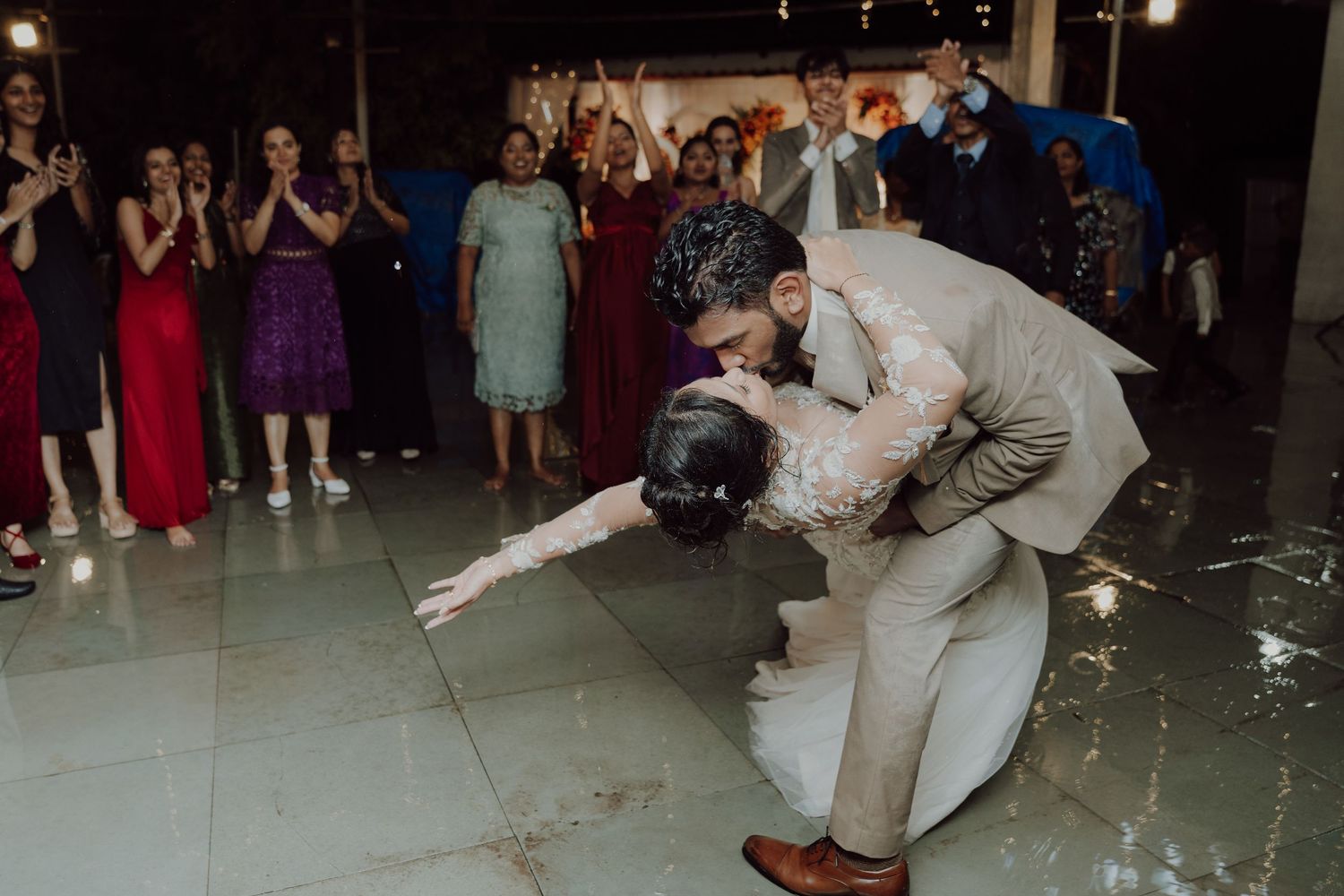 Groom dipping the bride during a wedding dance as cheering guests look on from the reception dance floor.