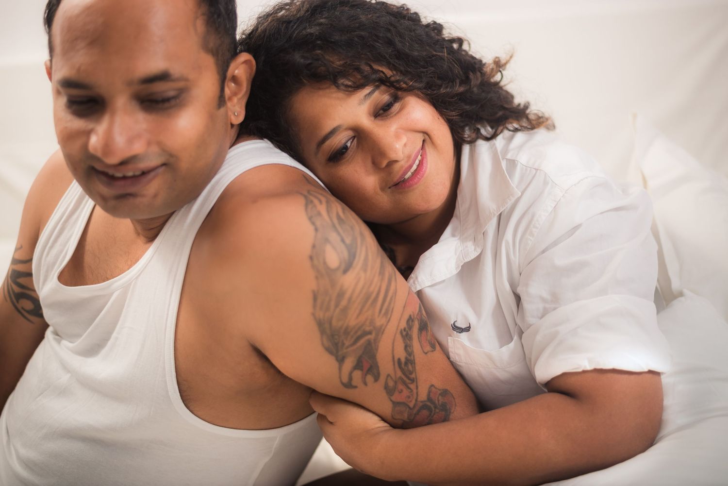 Happy couple in white tops share an affectionate moment together while relaxing at home.