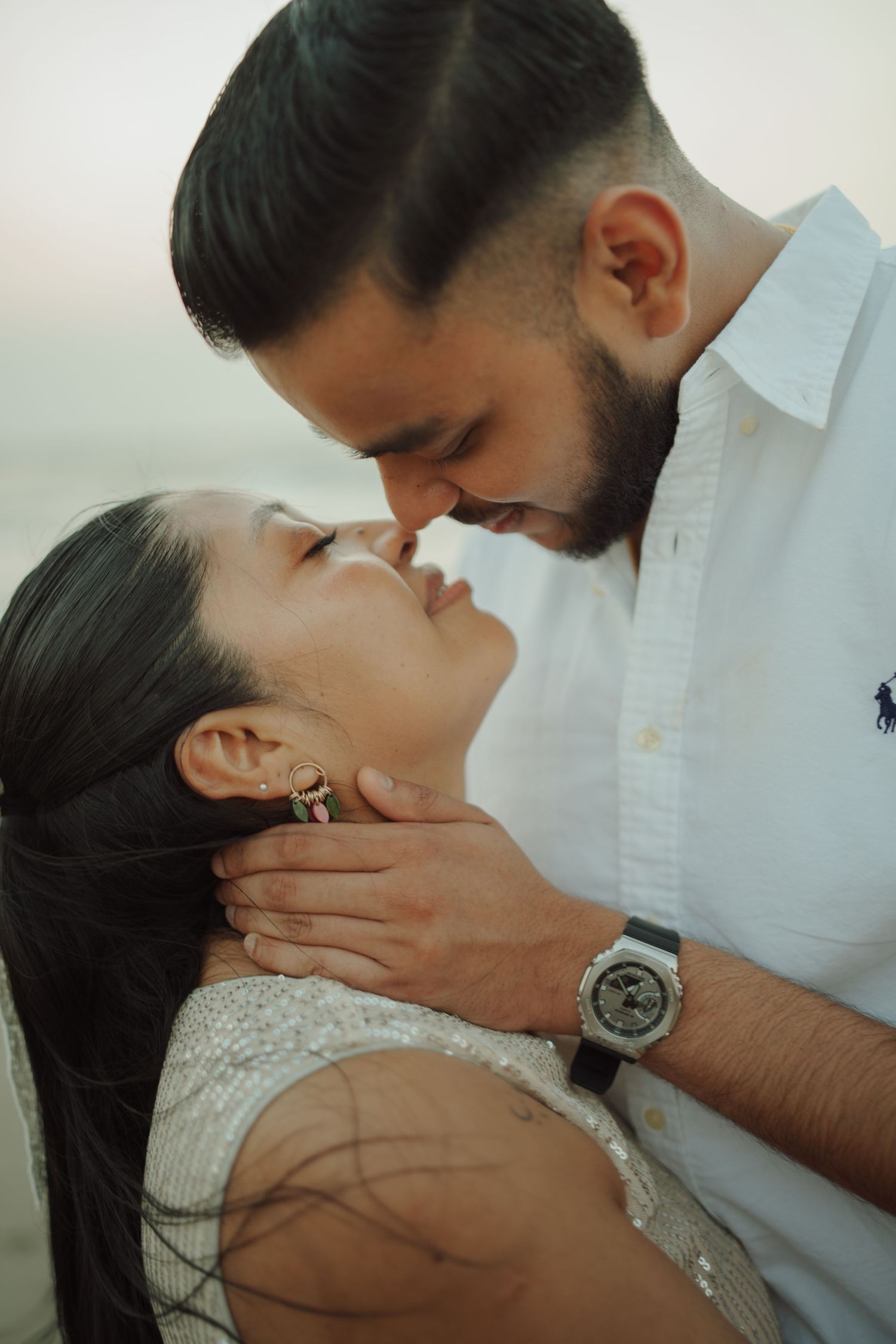 A romantic couple sharing an intimate moment, the man tenderly holding the woman's face as they lean in for a kiss.