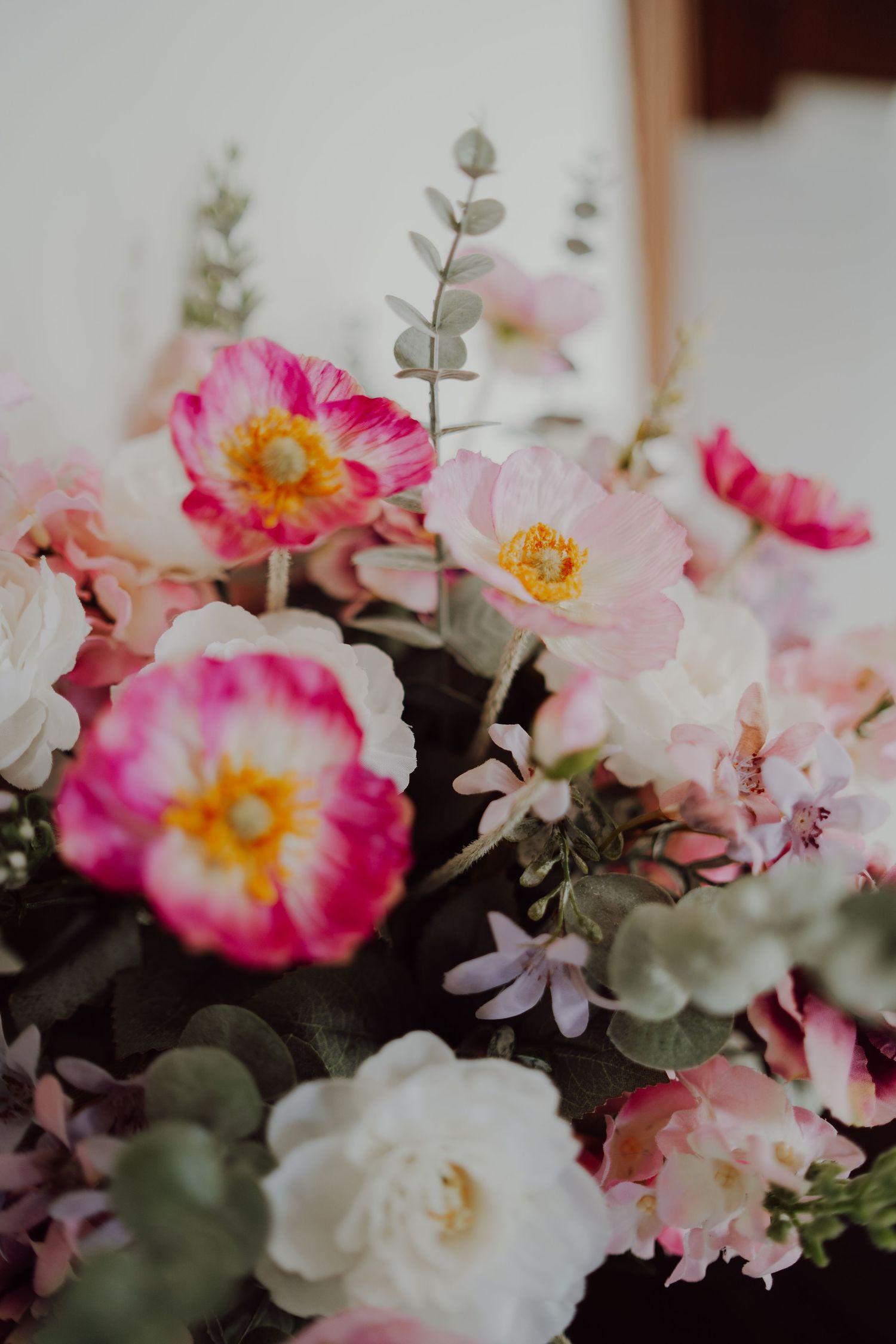 Close-up of pink and white flowers with eucalyptus leaves in a romantic arrangement.