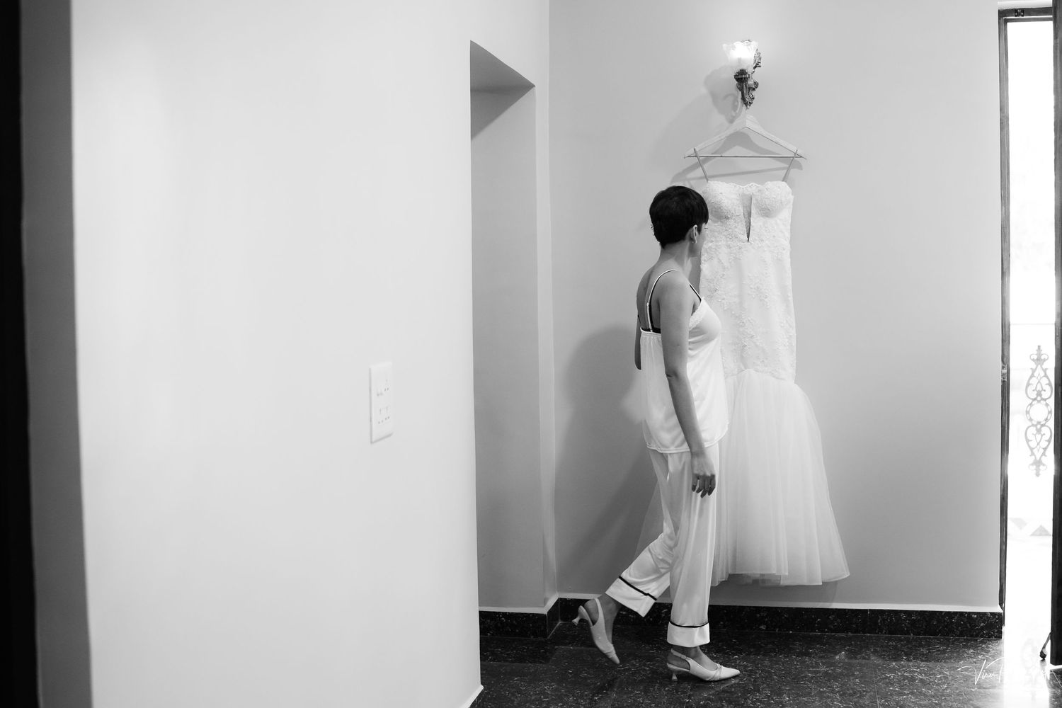 Minimalist white interior hallway with hanging dress and geometric shadows creating clean lines.