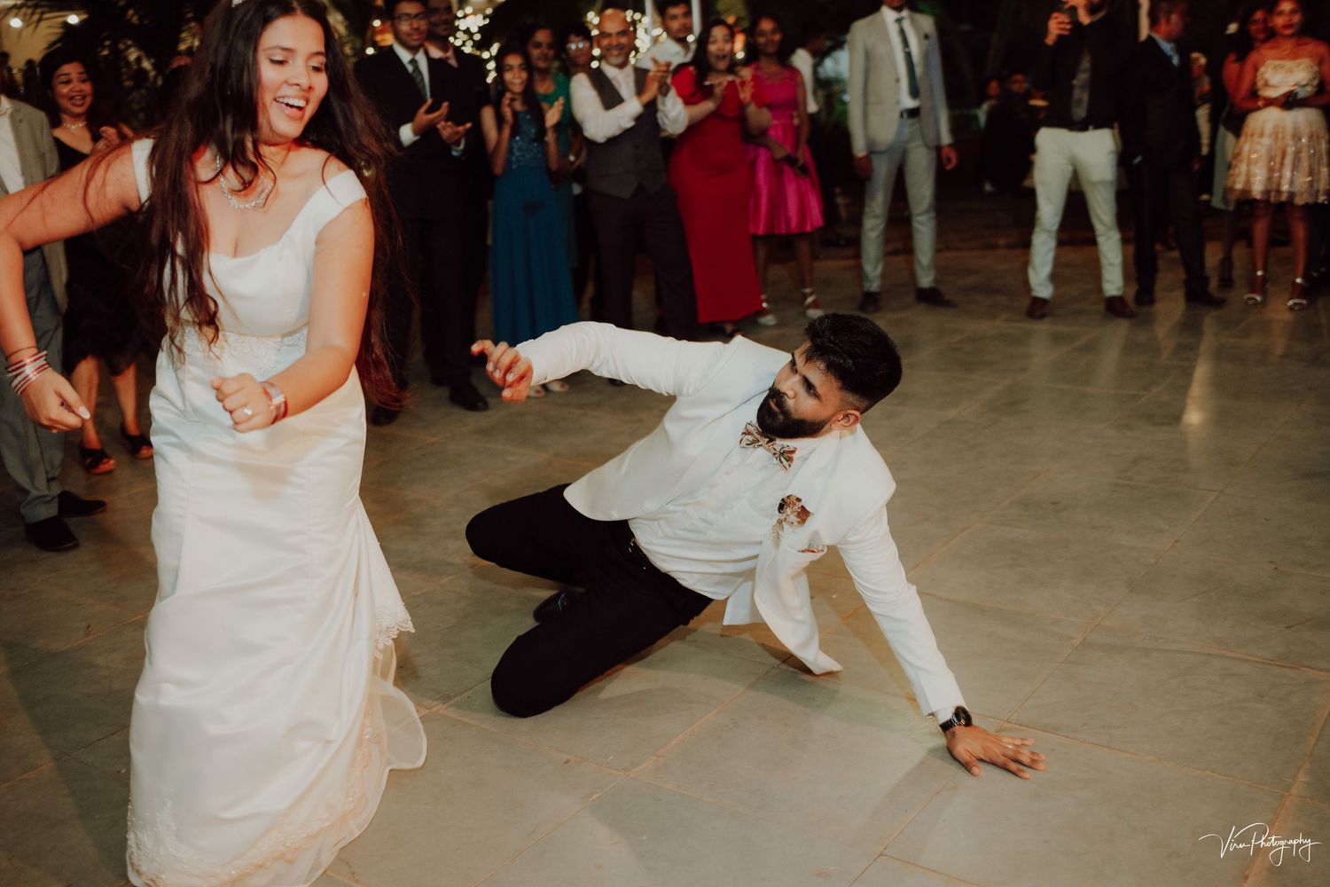 A couple performs a fun dance move at their reception with one person dramatically dipping to the floor.