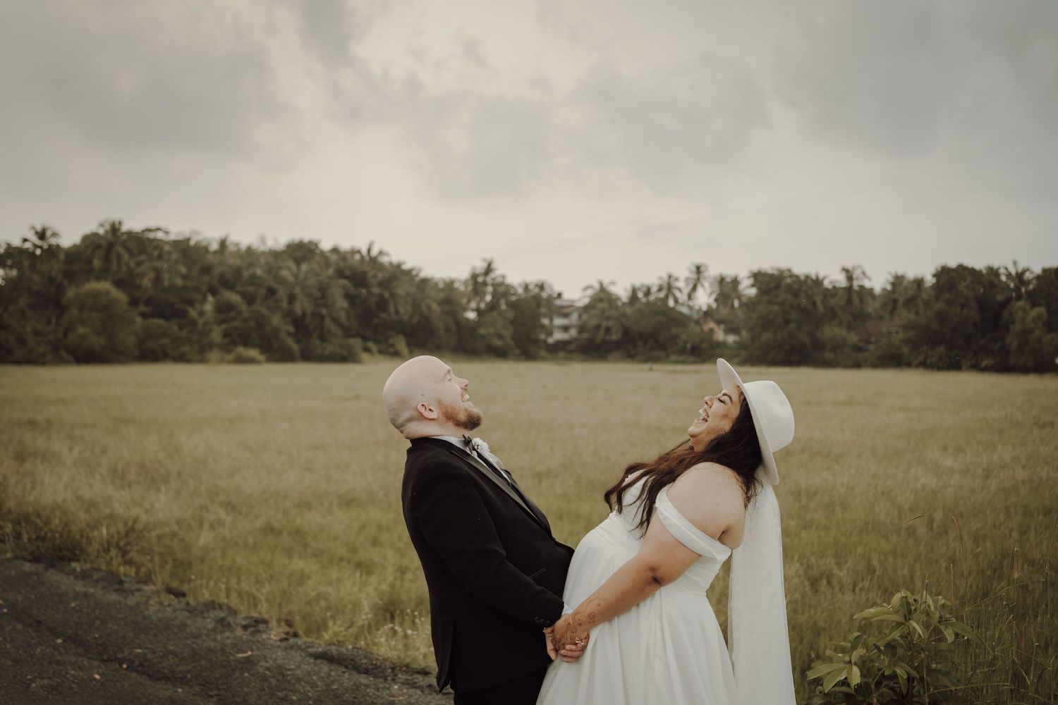 Candid wedding portrait of couple in open field with moody sky.
