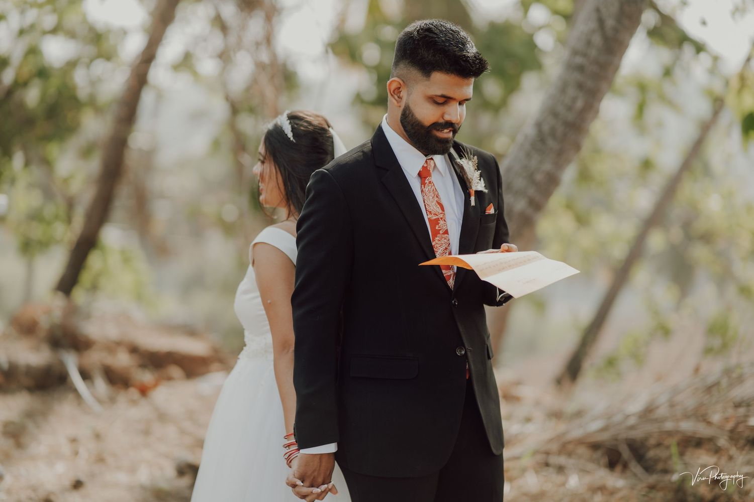 A couple shares a private first look moment in a wooded outdoor setting during their wedding ceremony.
